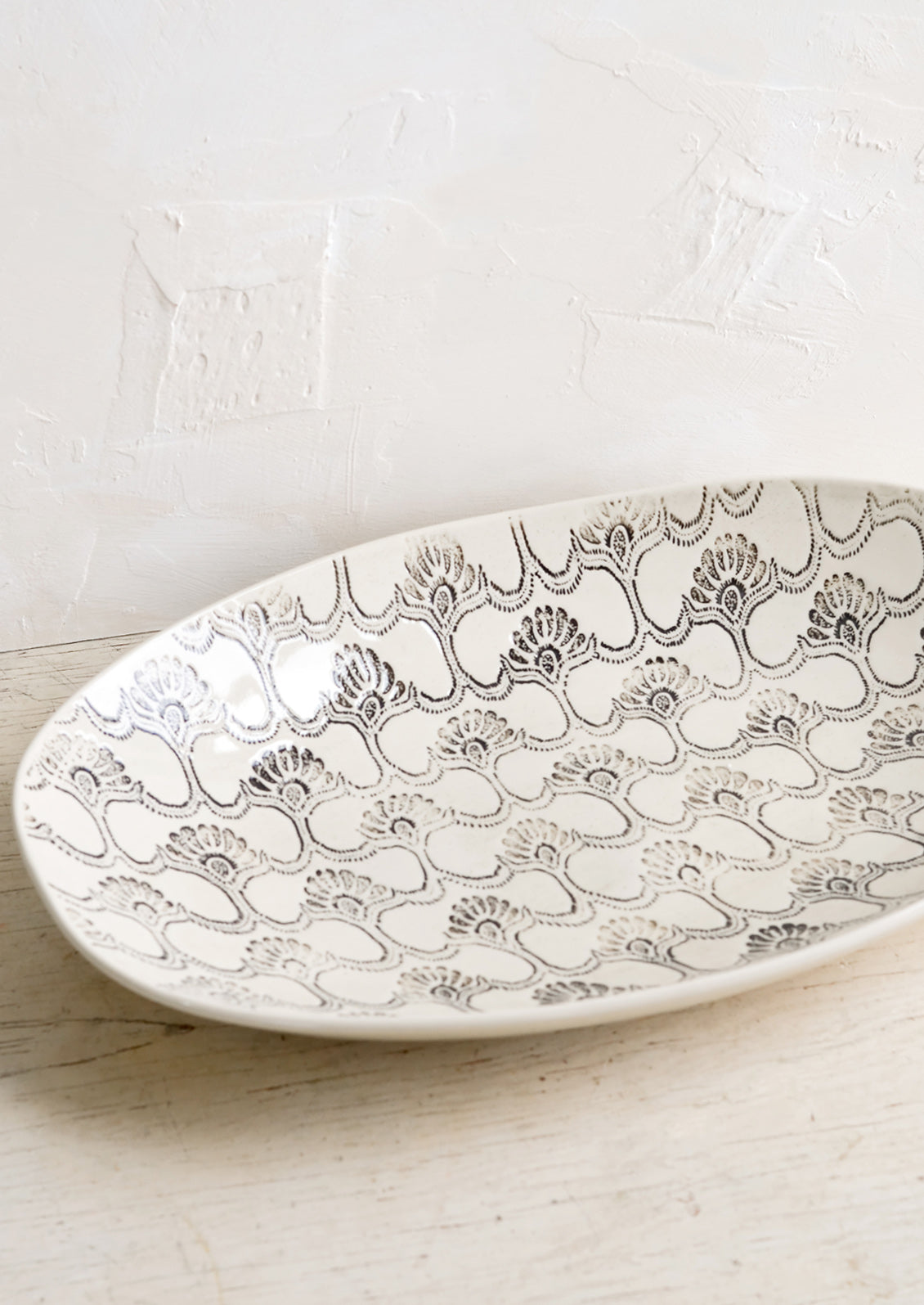 A large oval shaped ceramic platter with black and white textile pattern.