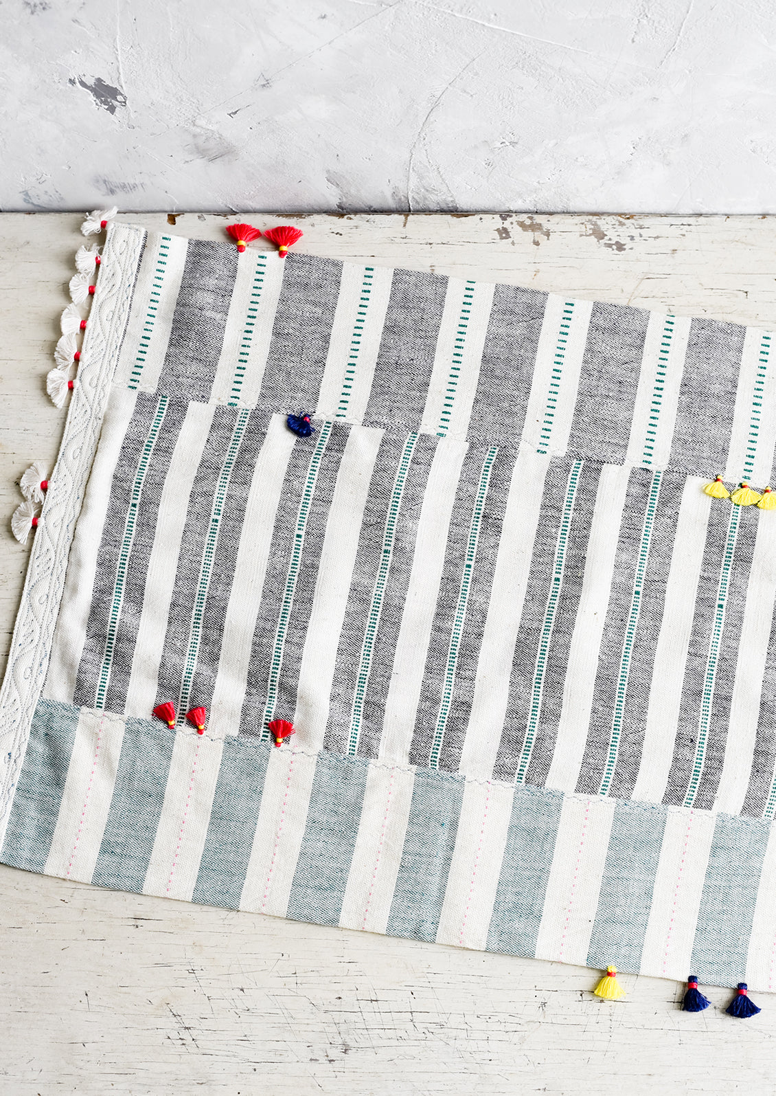 A madras stripe placemat in multicolor with tassel detail.