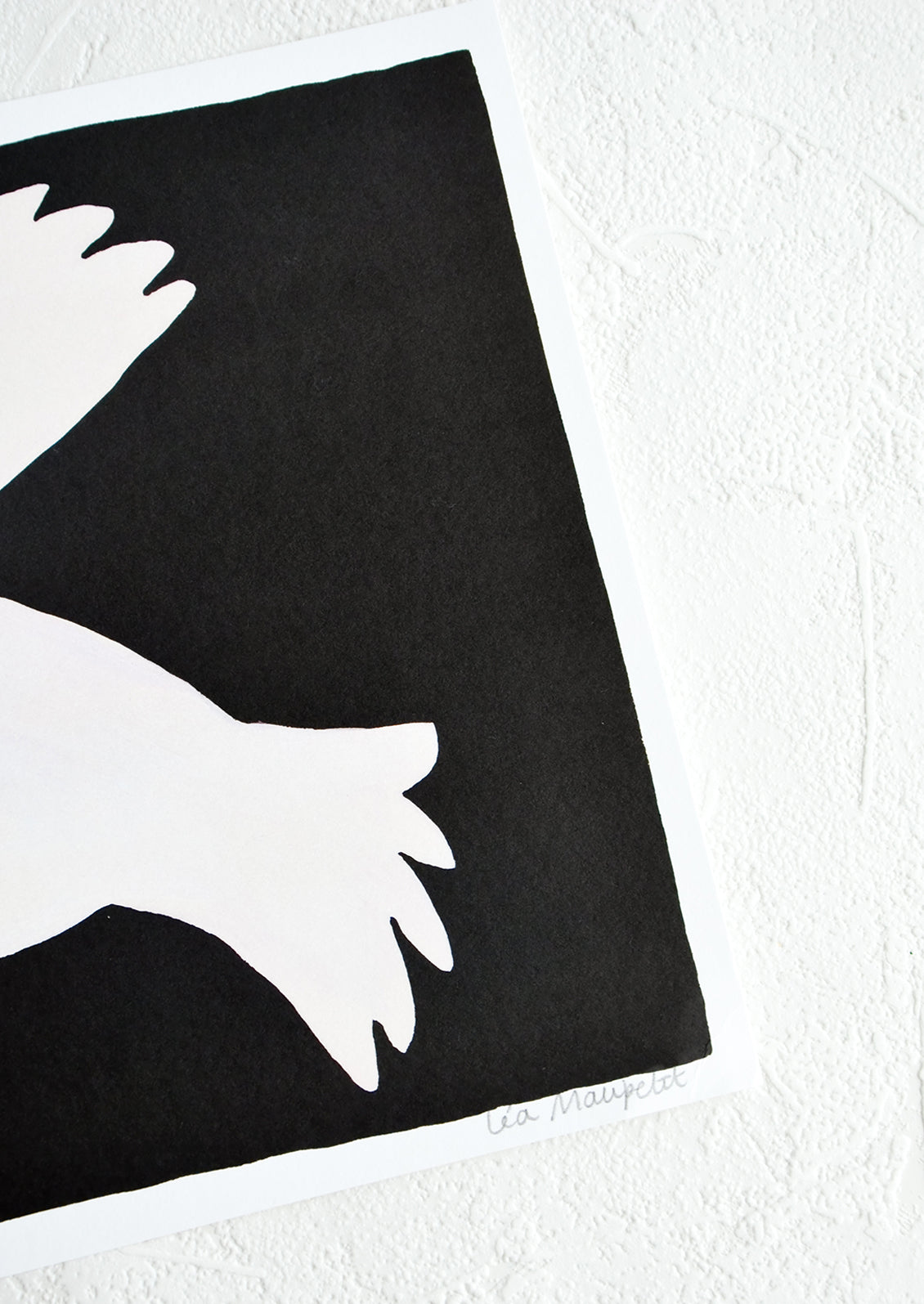 Artist's signature on corner of black and white art print.