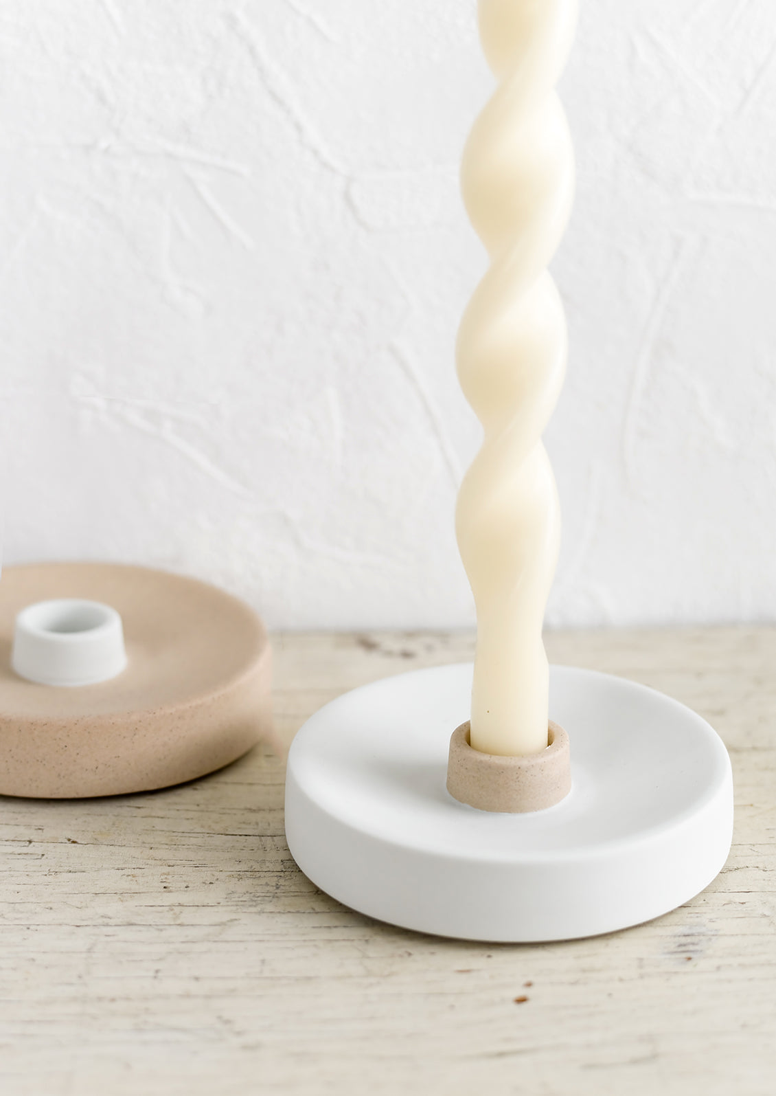 Neutral colored ceramic taper holders with ivory candle.