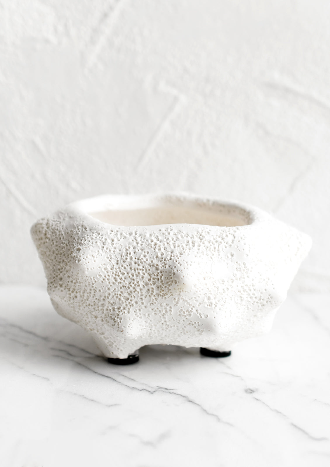 A small white ceramic planter with rough texture glaze and craggy, pointy shape.