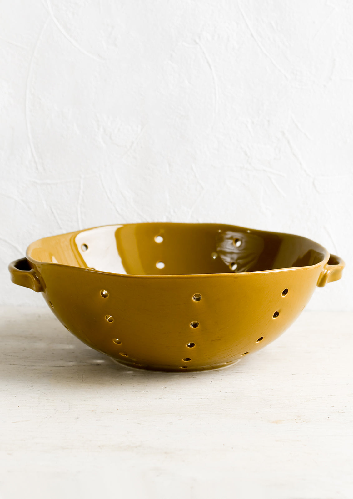 A large ceramic colander with side handles.