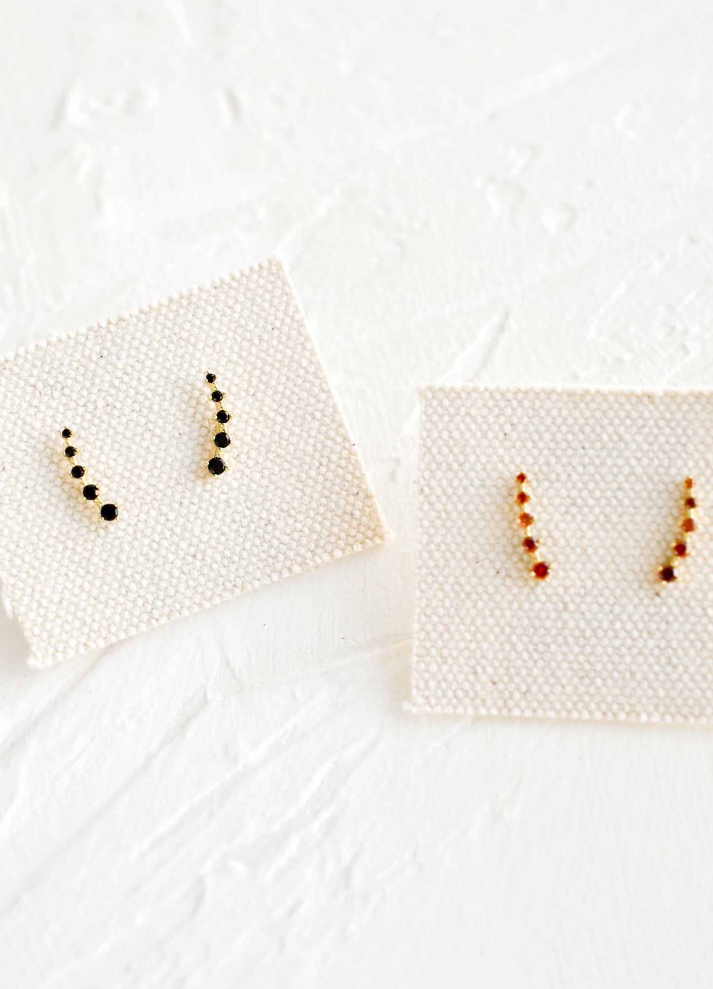 Black and amber crystal stud earrings on canvas cards.