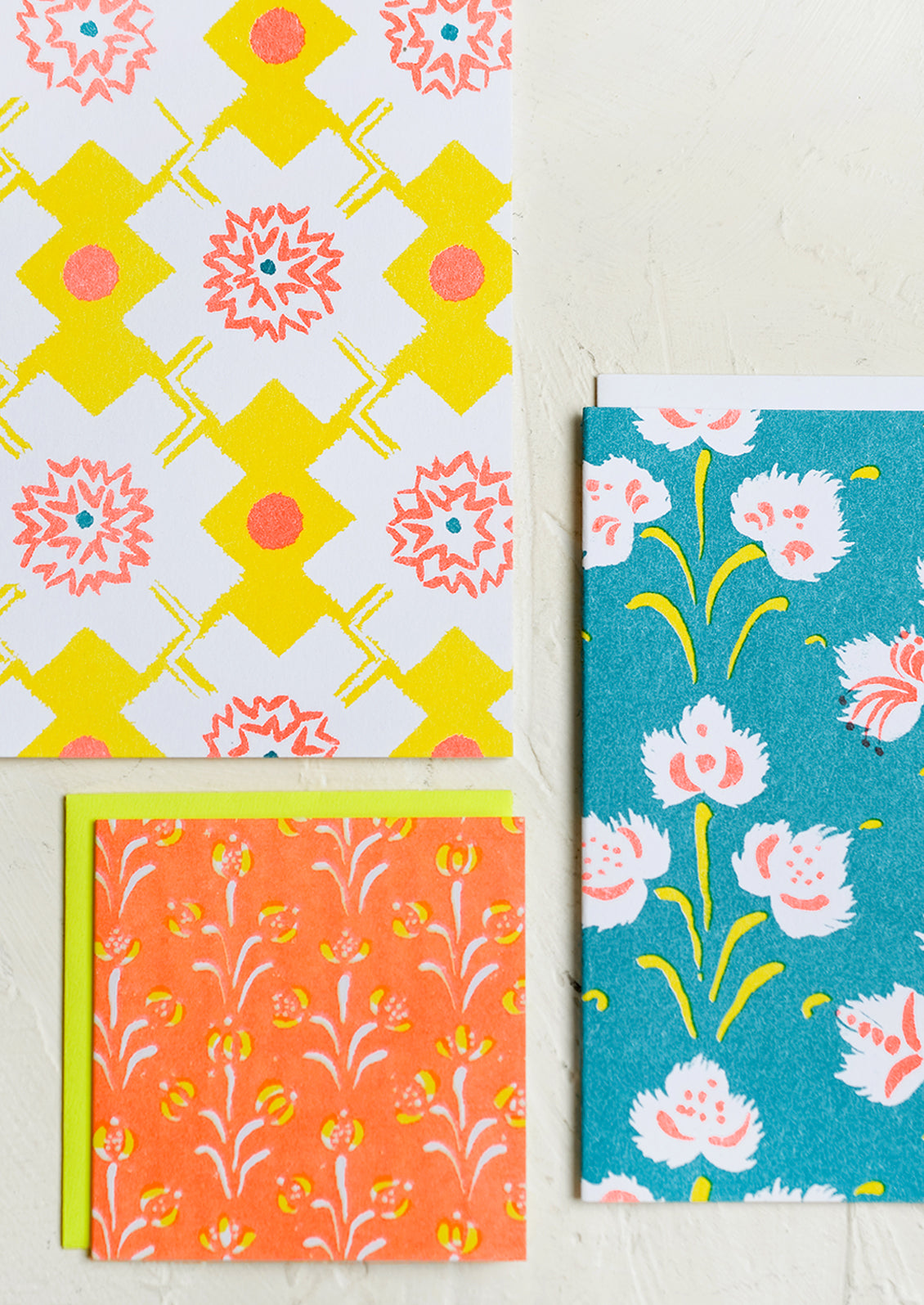 A patterned risograph printed card set in yellow, teal and orange.