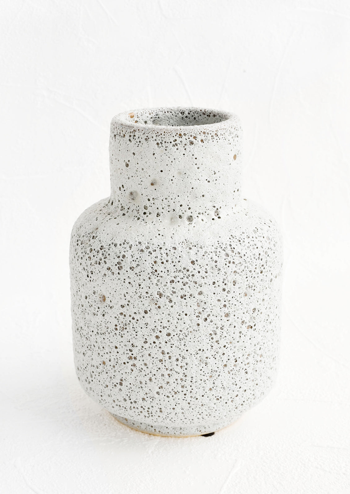 A ceramic vase in a heavily textured, crater-like light grey glaze with tapered opening.