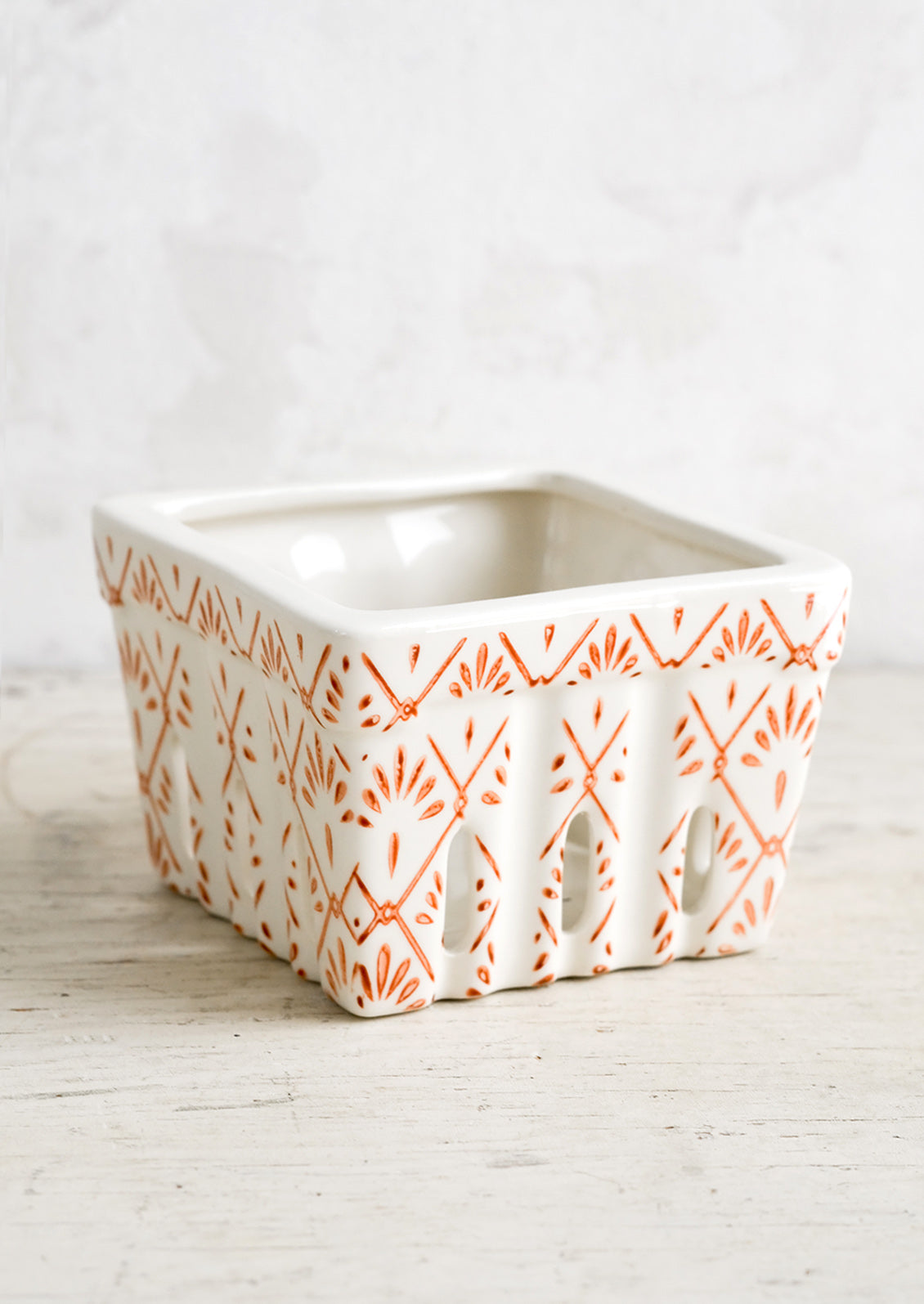 A ceramic berry basket with red tilework print on white ceramic.