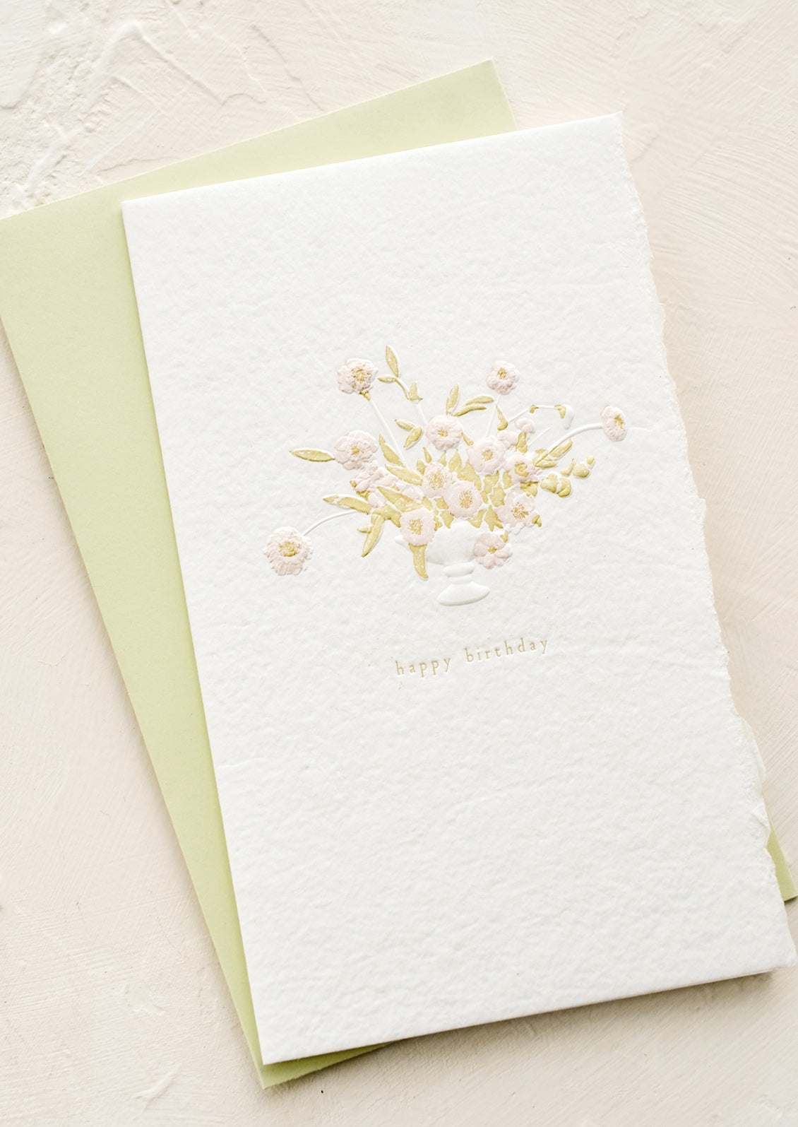 A greeting card in handmade white paper with floral vase imagery and "Happy Birthday" text.