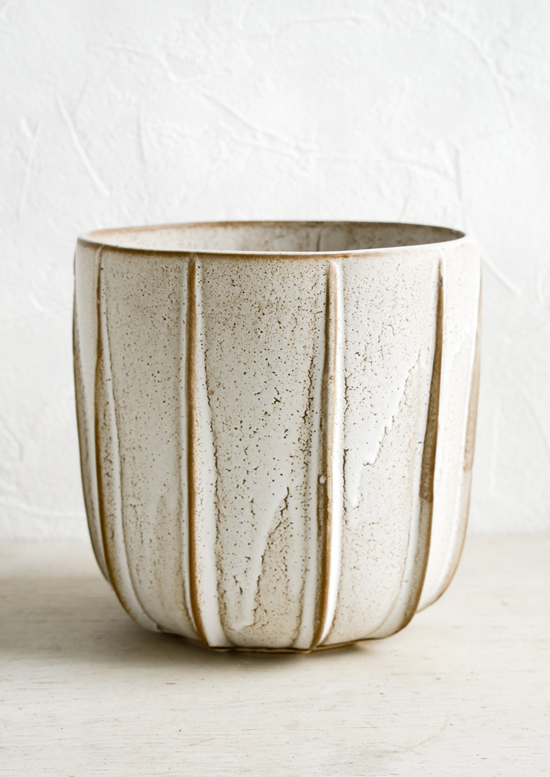 A tan ceramic planter with decorative raised grooves.