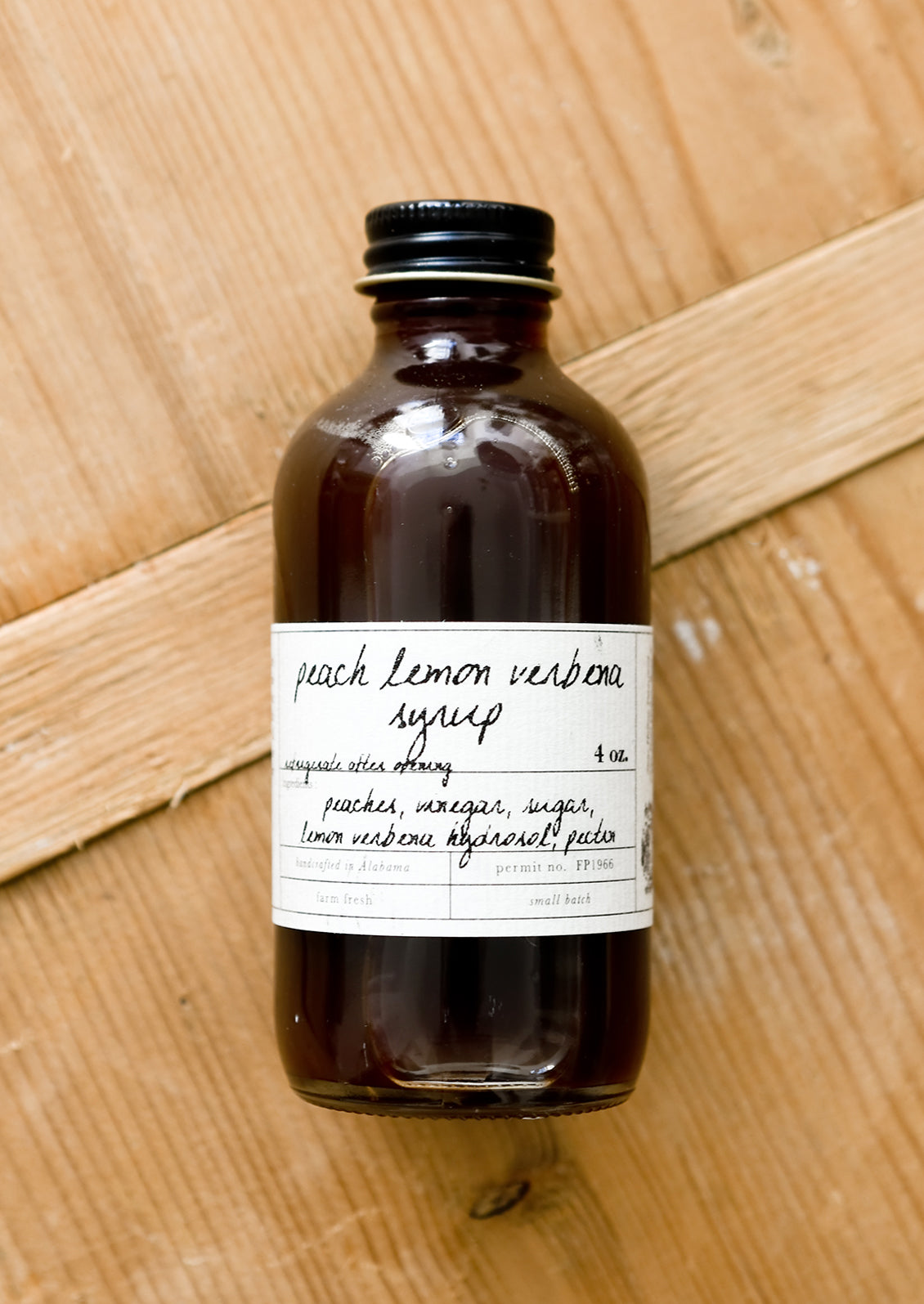 A glass bottle of peach lemon verbena syrup.