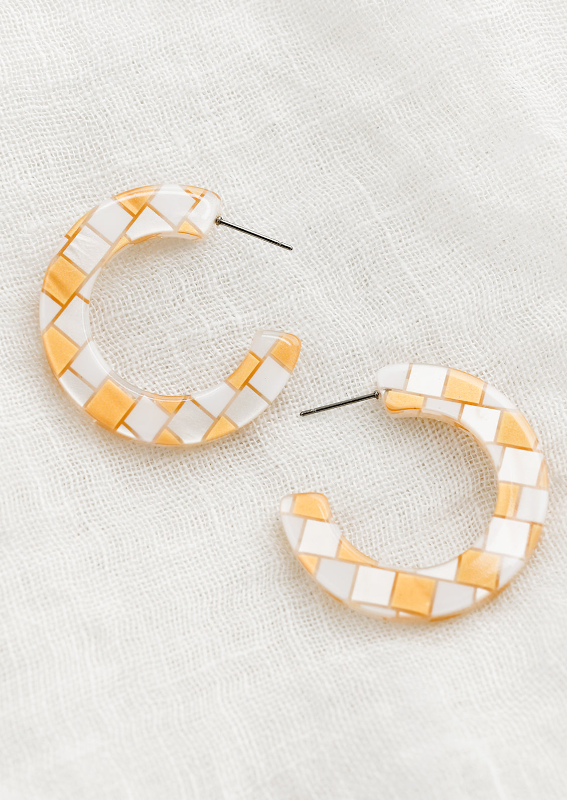 A pair of checkered earrings in gold.