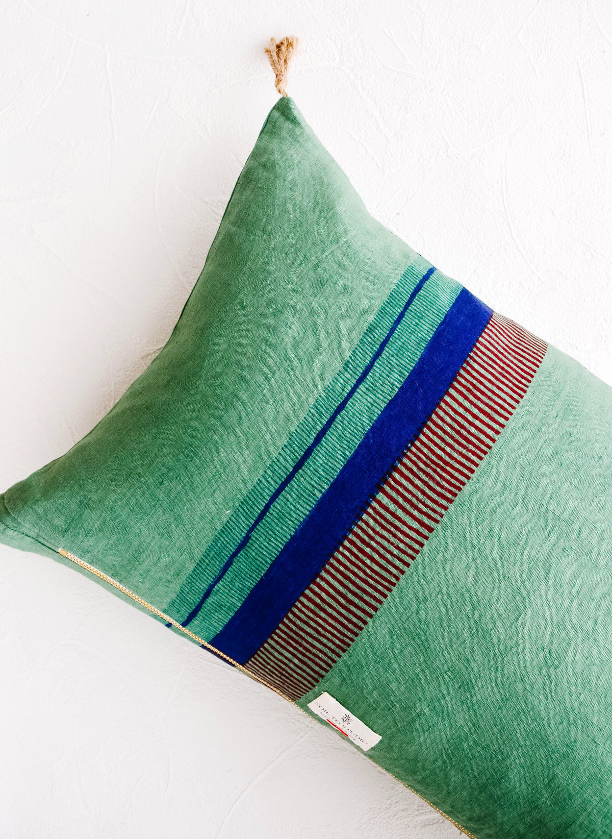 Back of linen throw pillow showing a series of block printed stripes and exposed brass zip closure
