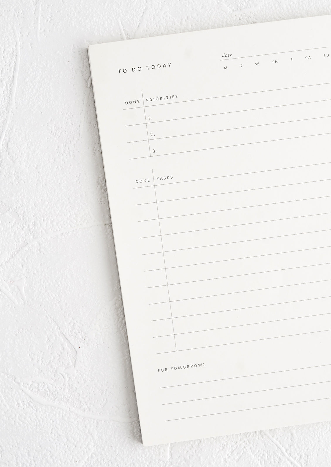 A white notepad with guided prompts for listing daily tasks and priorities.