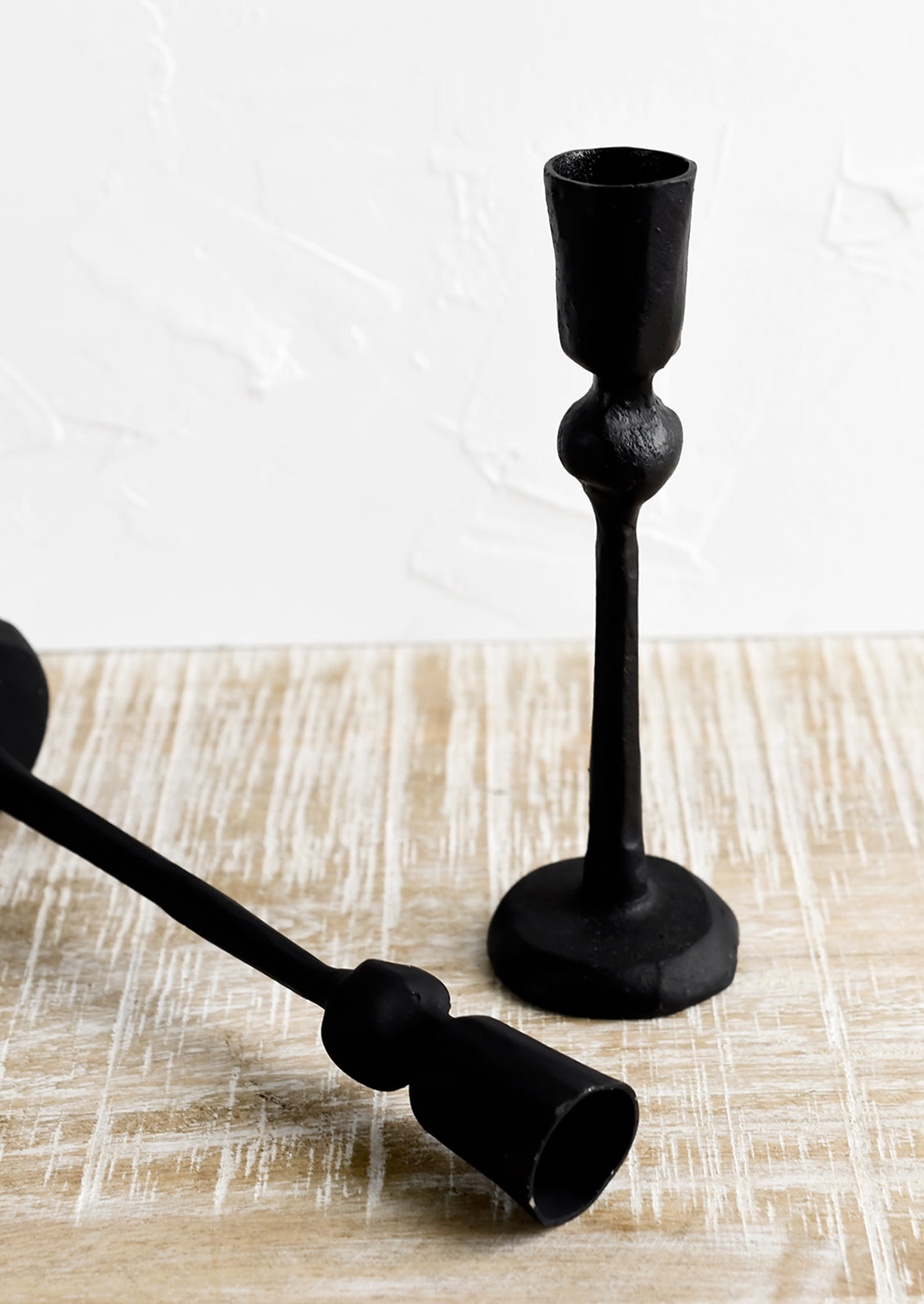 Black cast iron candle holders in spindly, carved silhouette.