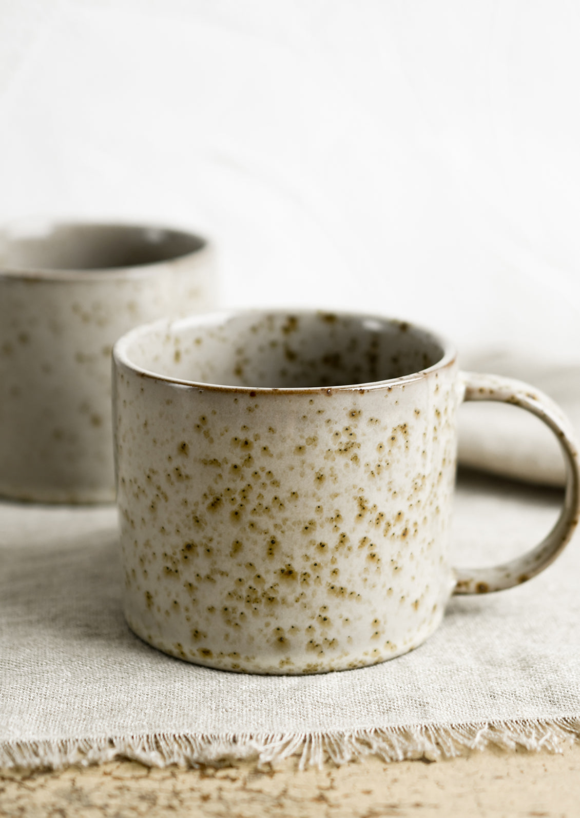 A brown speckled coffee mug with round handle.