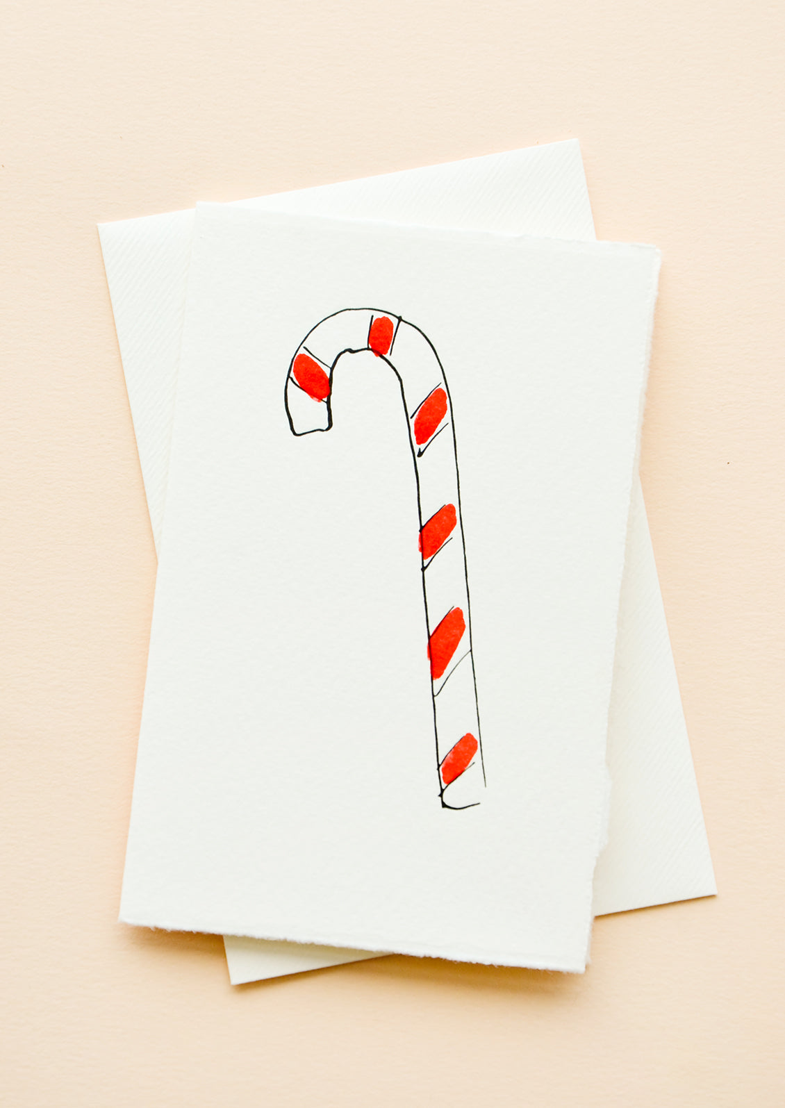 A white greeting card with illustration of a candy cane, with a white envelope.