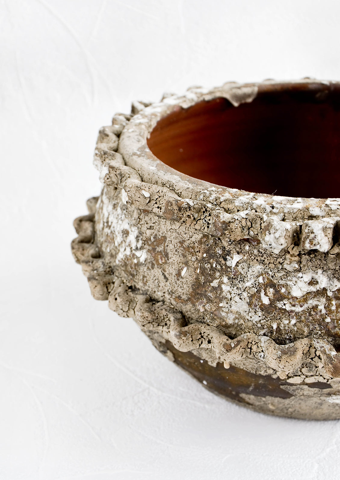 Distressed ceramic planter in chippy brown and white glaze with textured applique