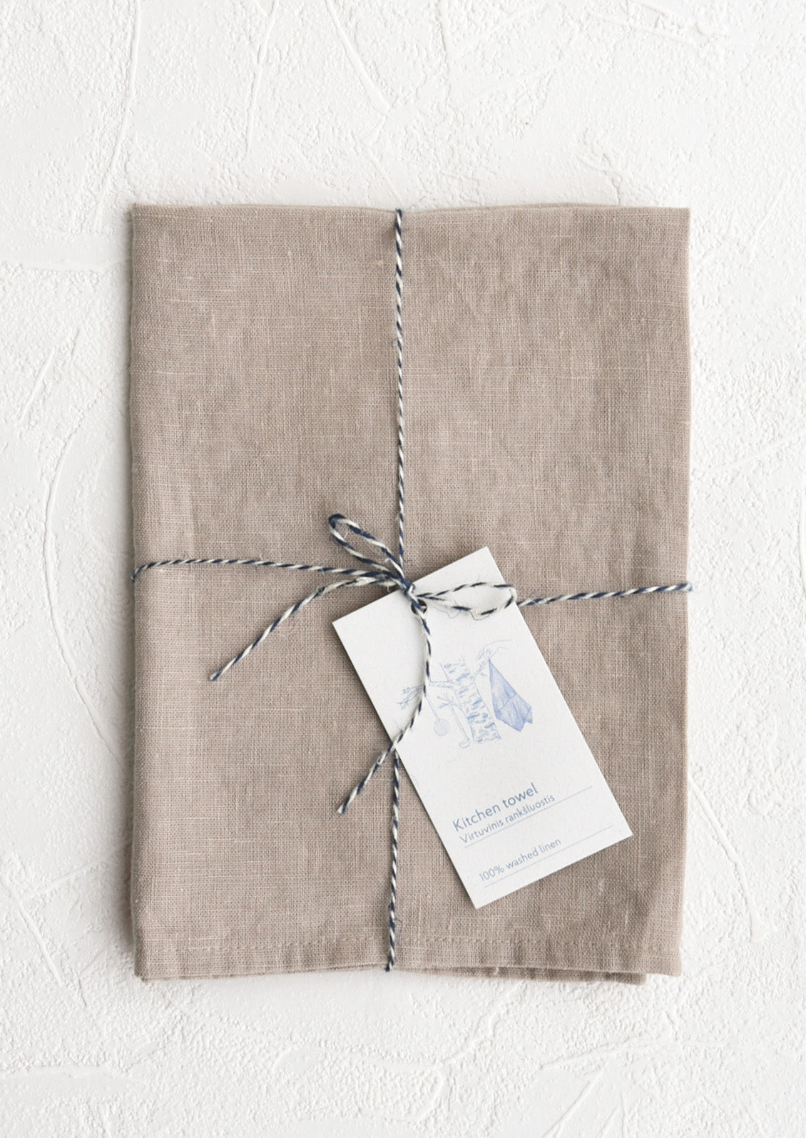 A folded faded pale mauve linen tea towel tied in baker's twine with a decorative hangtag