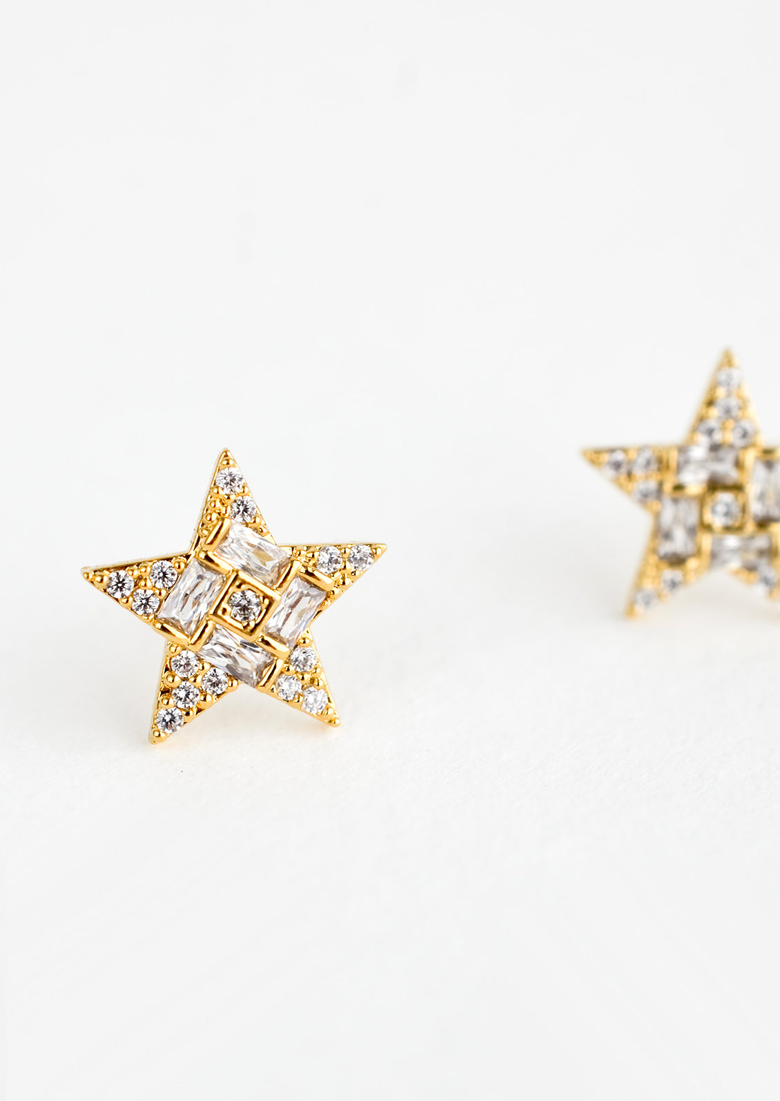 A pair of gold star shaped stud earrings with crystal pave detailing.