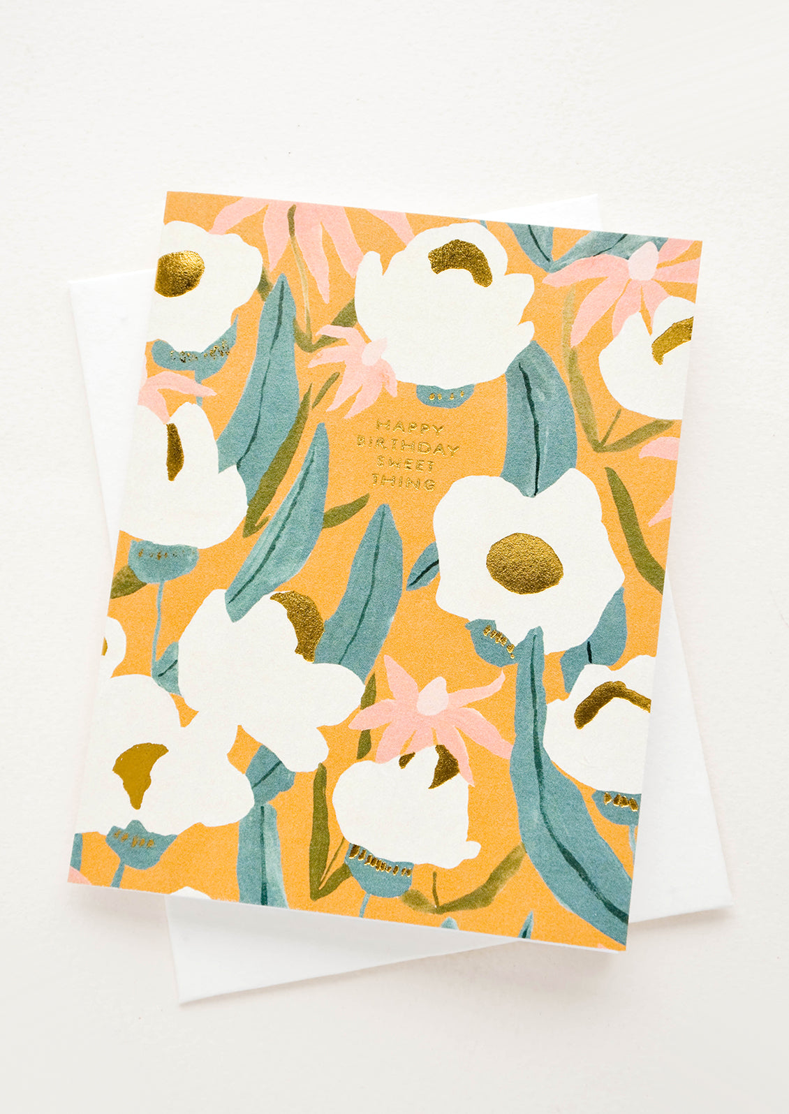 Greeting card with flowers on mustard colored background, small golden lettering reads "Happy Birthday Sweet Thing"