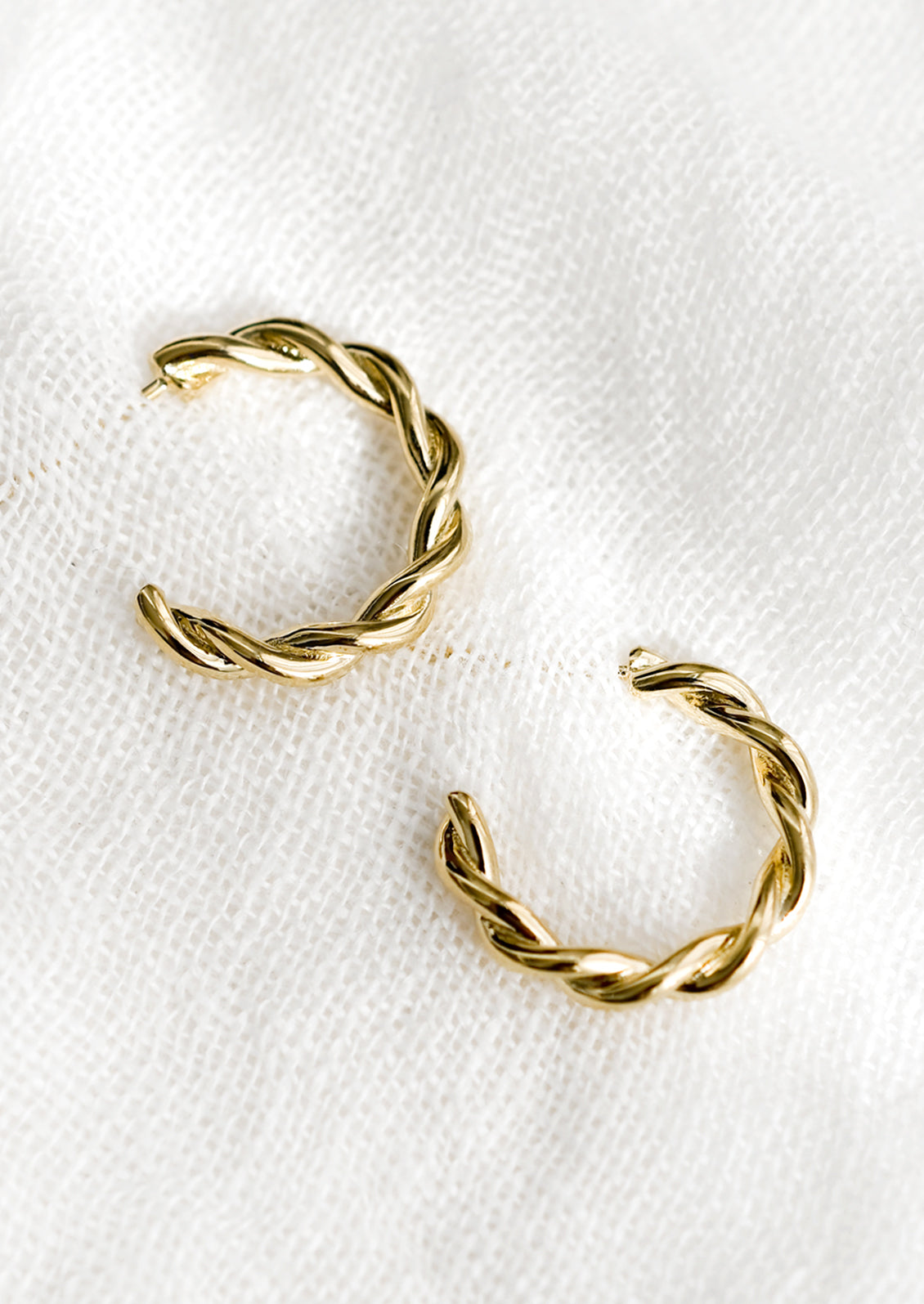 A pair of gold twist hoop earrings.