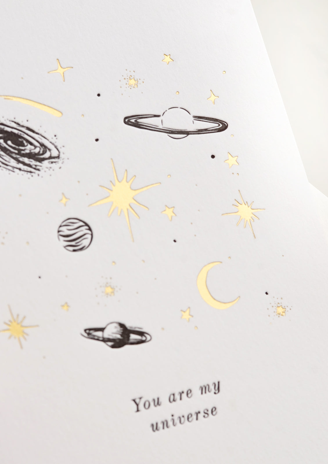 A greeting card with black and gold planets and text reading "You are my universe".