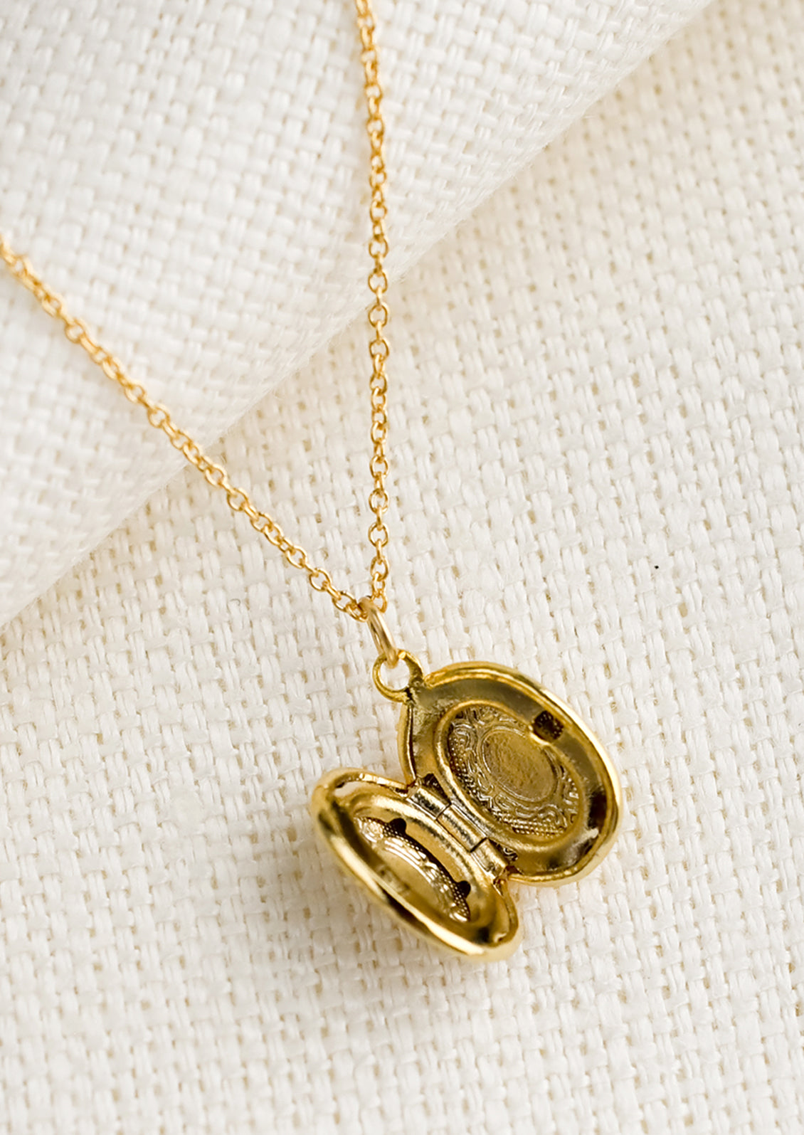 A oval shaped locket necklace with antique inspired engraving.