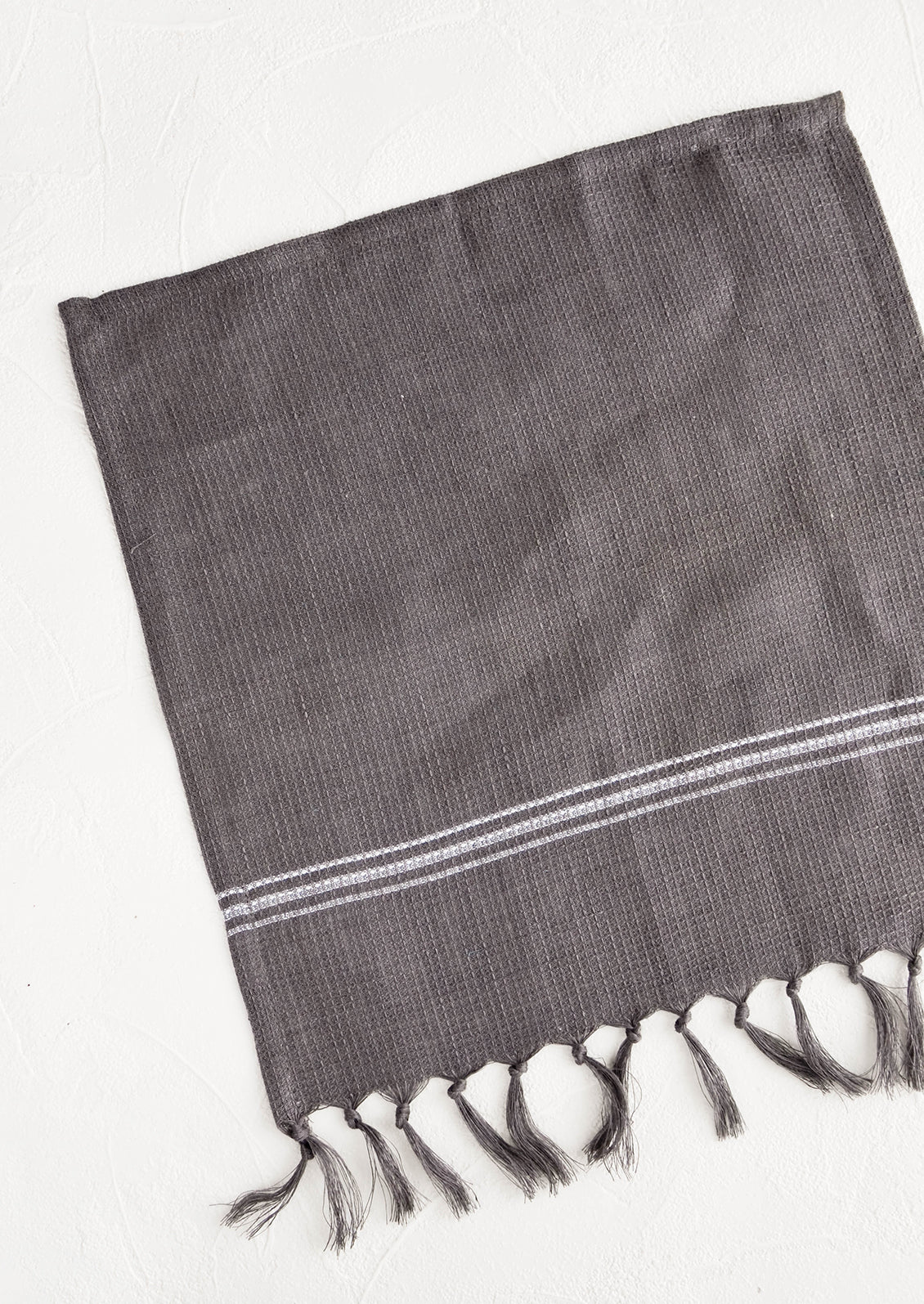 Waffle-textured dishcloths in charcoal color with single white stripe detail and tassel trim