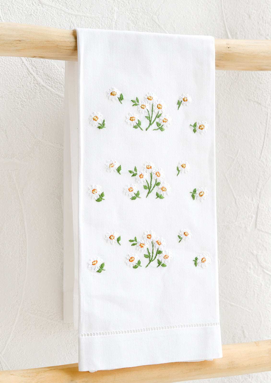 A white folded cotton hand towel with embroidered floral design.