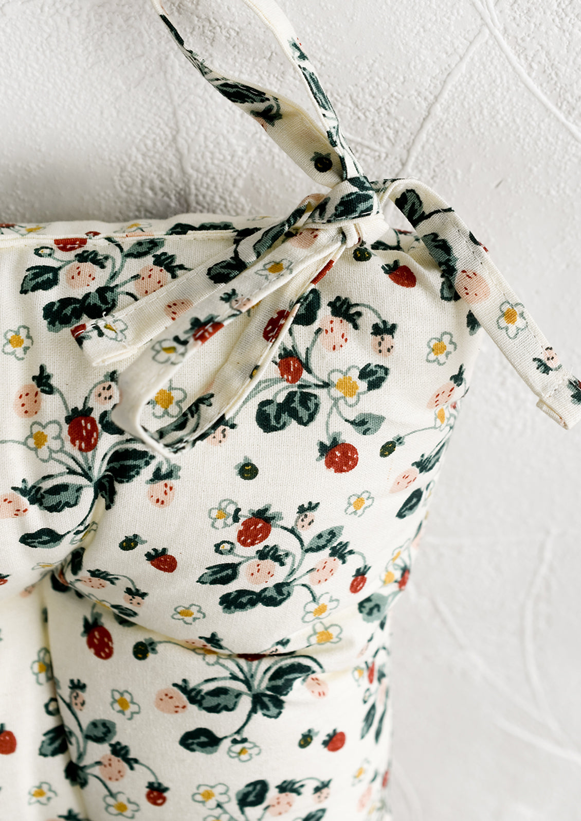 A square, quilted strawberry print chair cushion with corner ties.