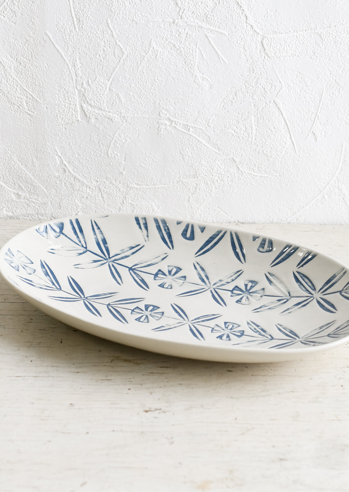 An oval shaped ceramic platter with blue imprint design.