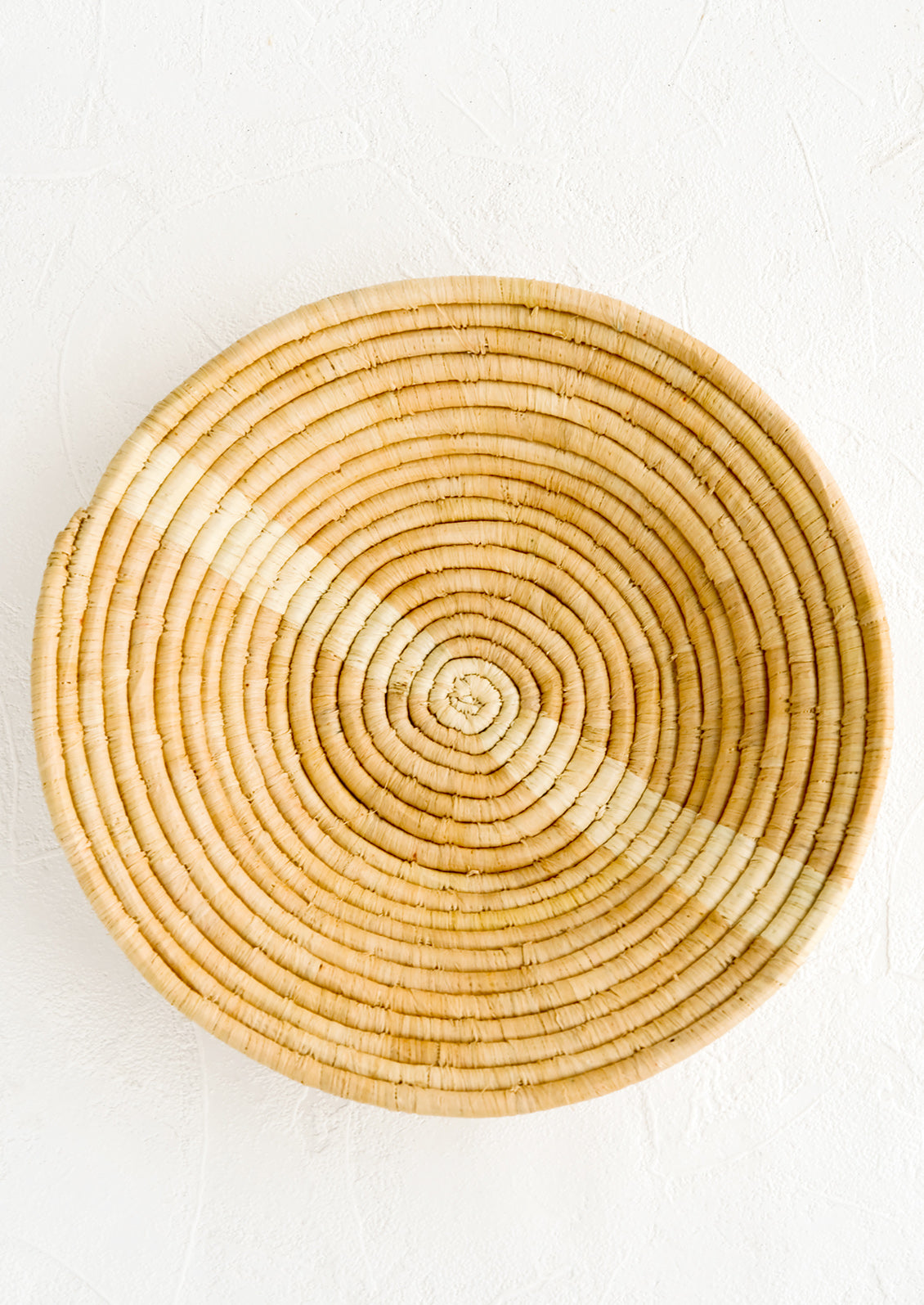 Tan woven raffia bowl with natural streak across middle