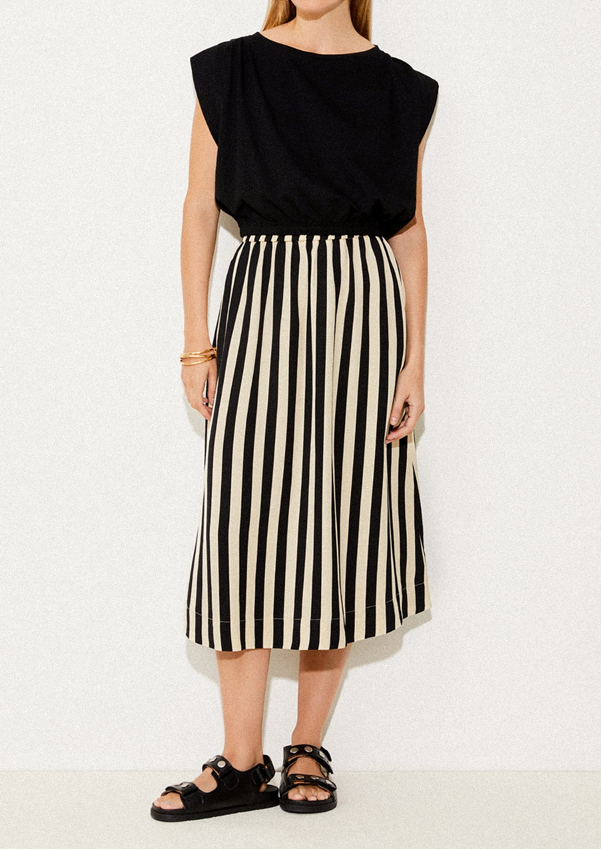 A person wearing a beige and black vertical stripe skirt.