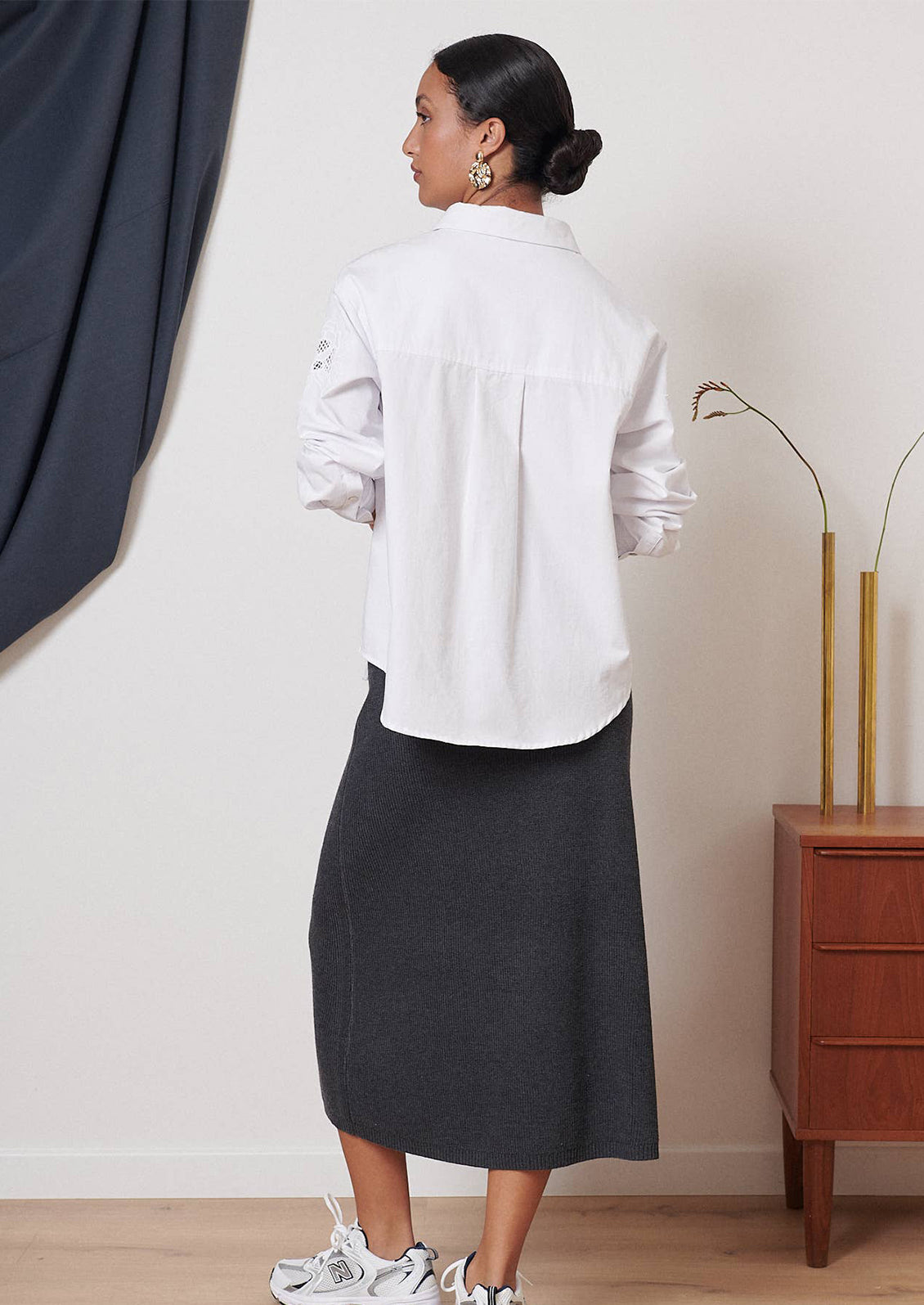 A woman wearing a white button down shirt with eyelet embroidery at yoke.