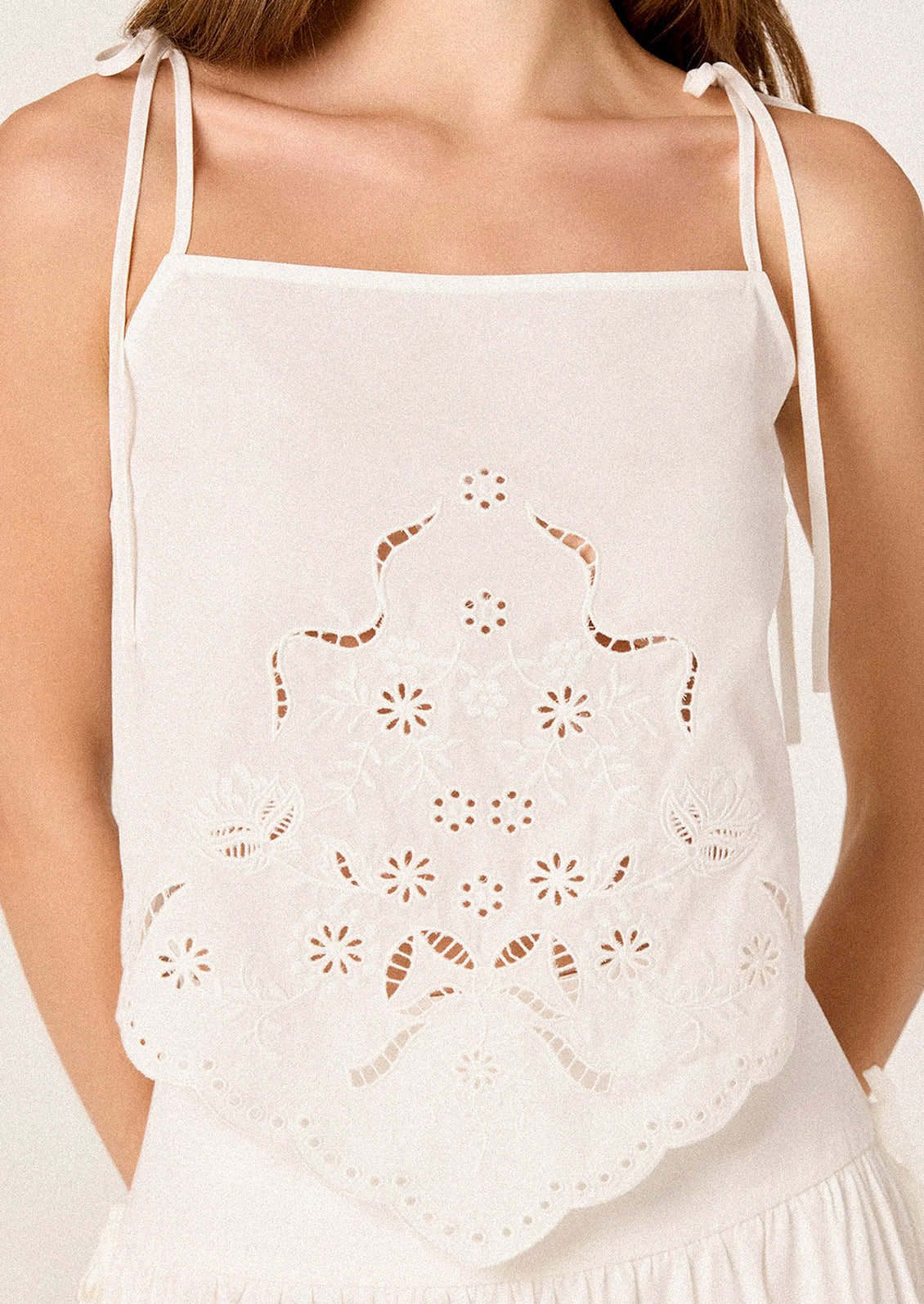 White lace top worn by a person on a plain background