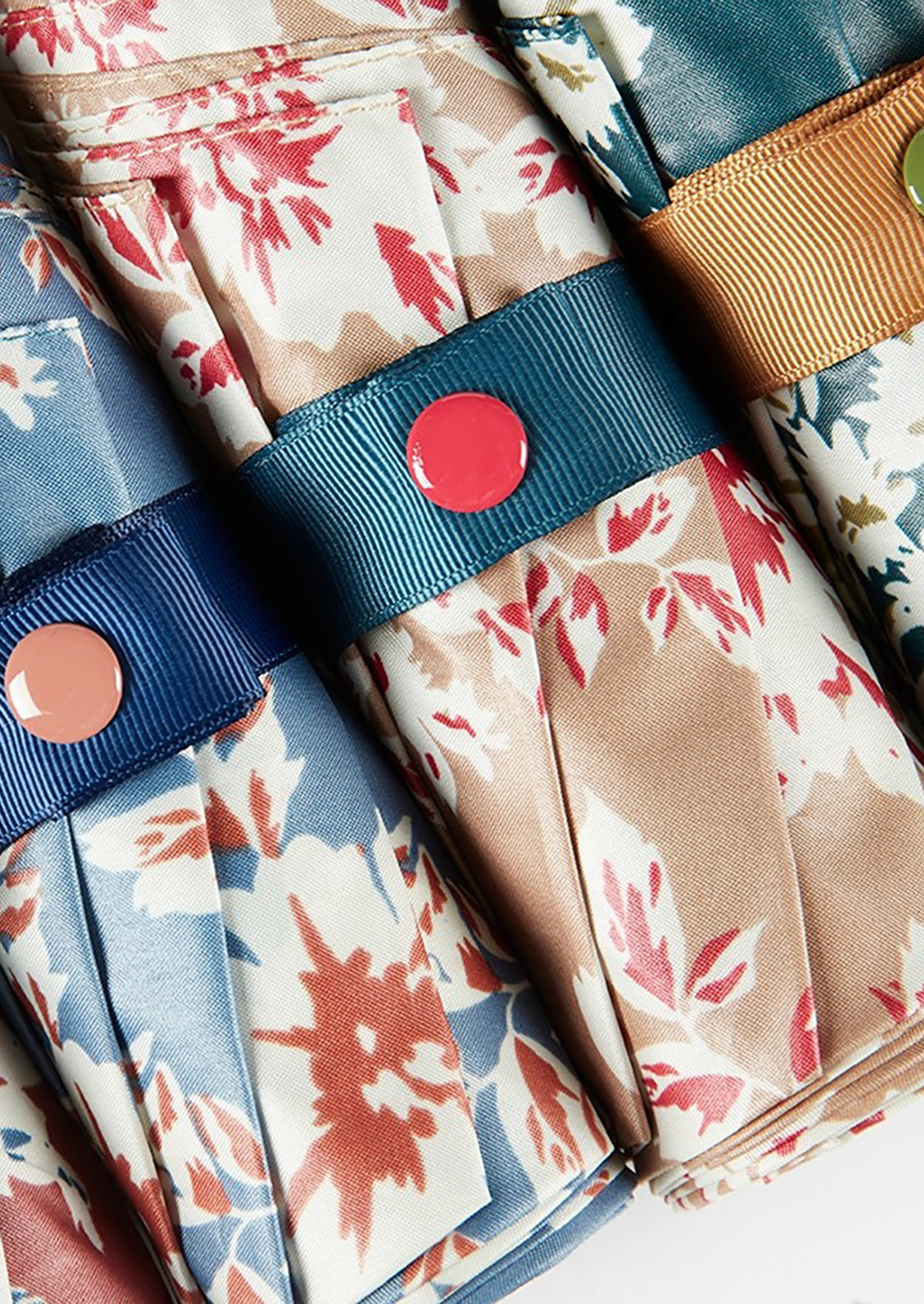 Floral print umbrellas with contrasting snap closure.