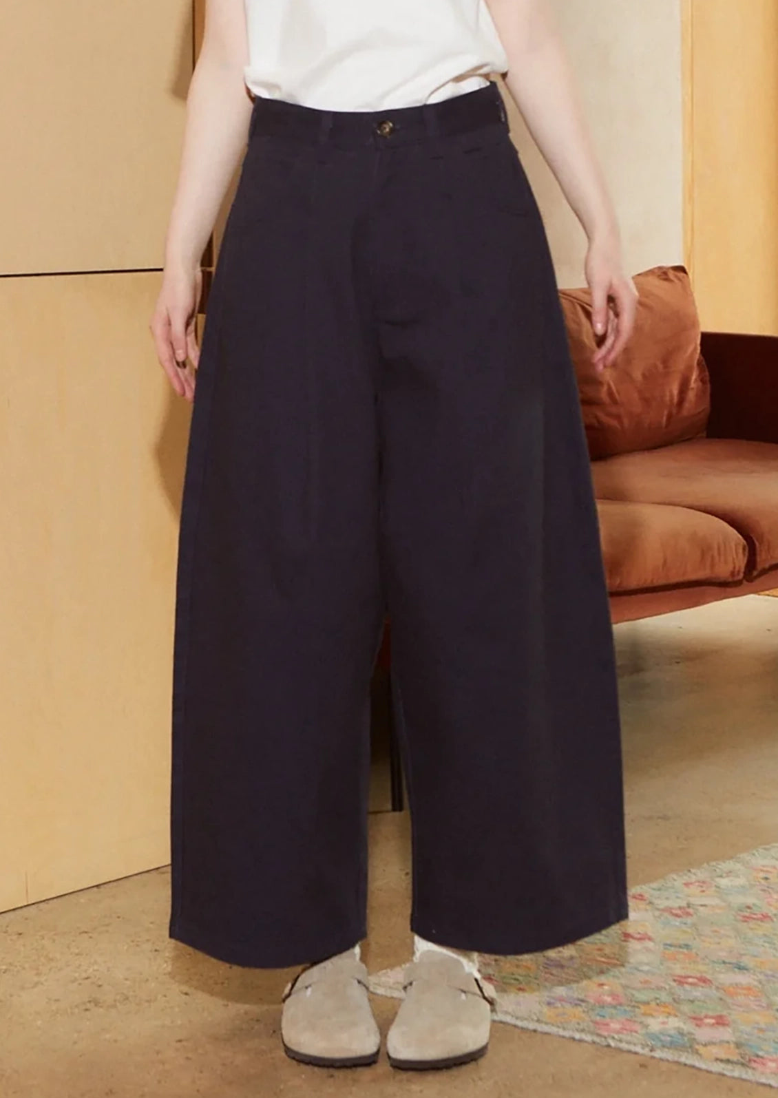 A woman wearing a pair of pleat front, balloon leg jeans in navy blue color.