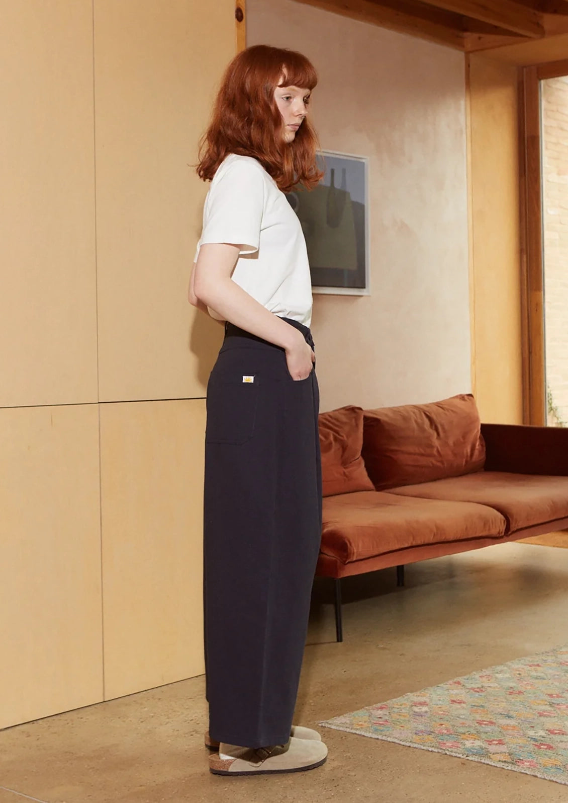 A woman wearing a pair of pleat front, balloon leg jeans in navy blue color.