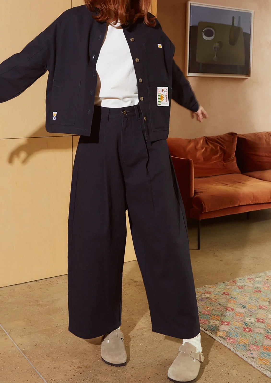 A woman wearing a pair of pleat front, balloon leg jeans in navy blue color.