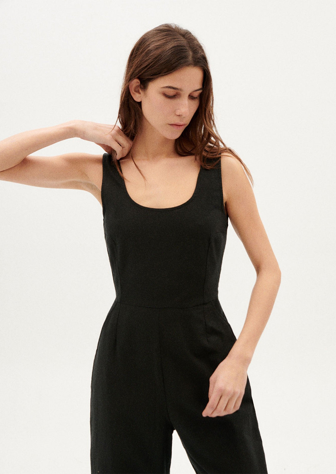 A woman wearing a black one piece jumpsuit with scoop neck.