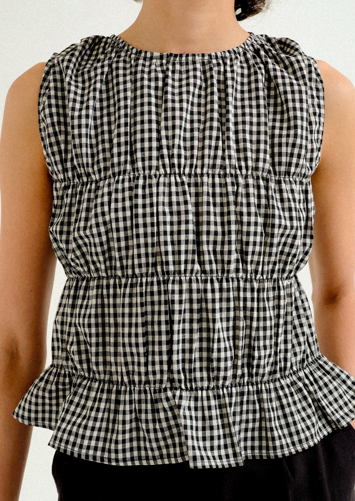 A woman wearing a black and white gingham sleeveless top.