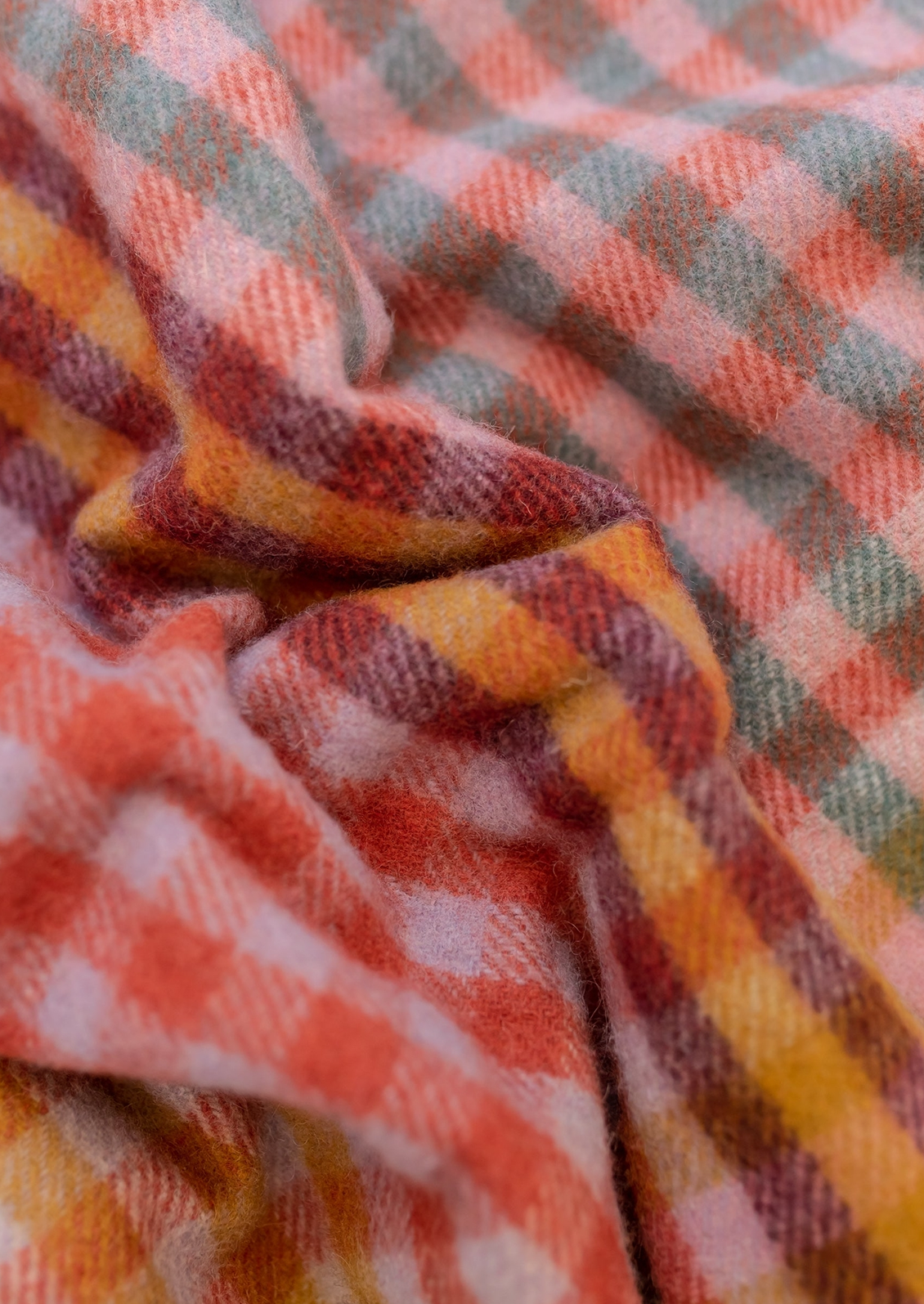 A colorful gingham check blanket in tones of lilac, magenta, and yellow.