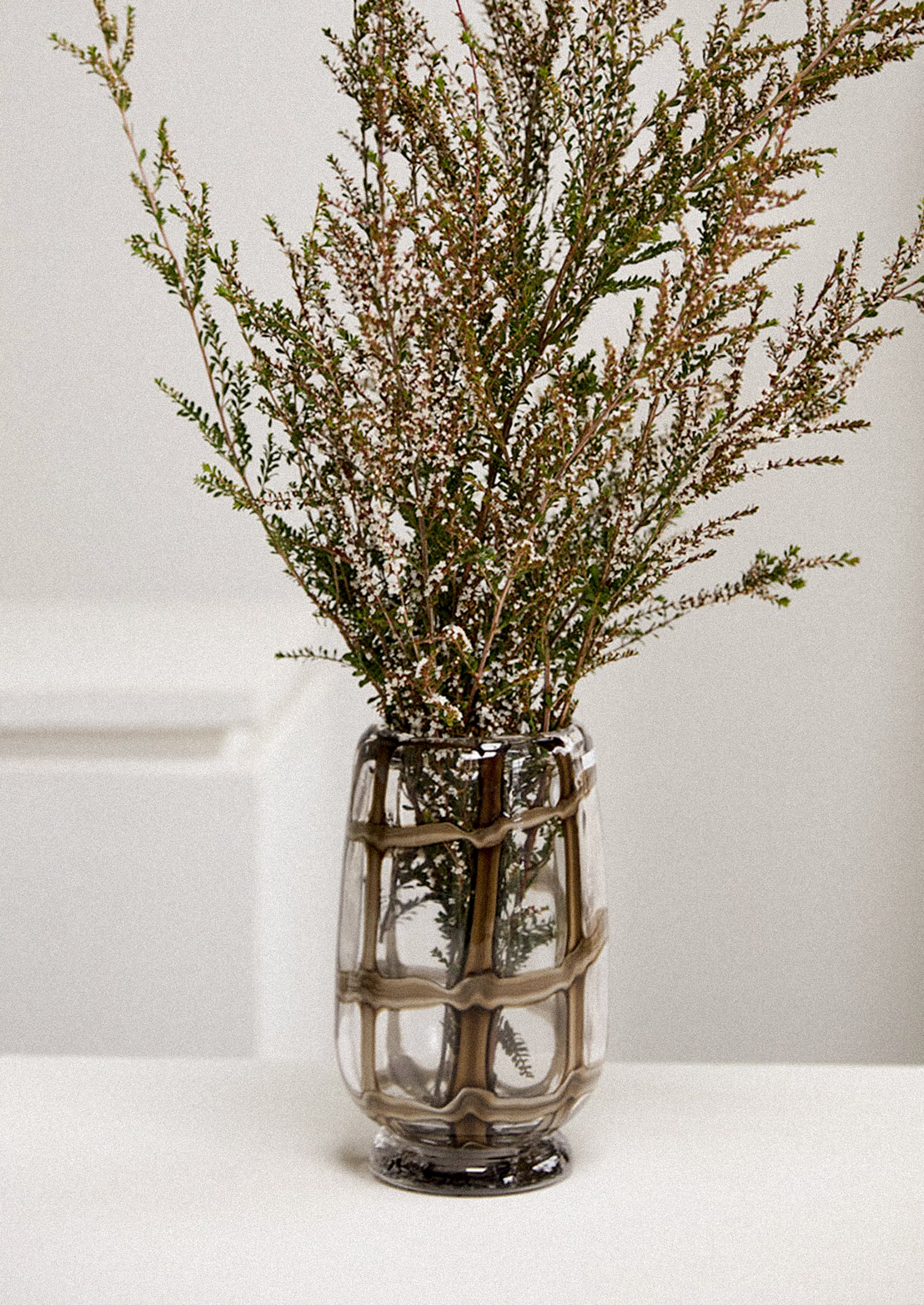 A cylindrical glass vase with footed base, in clear glass with brown grid pattern.