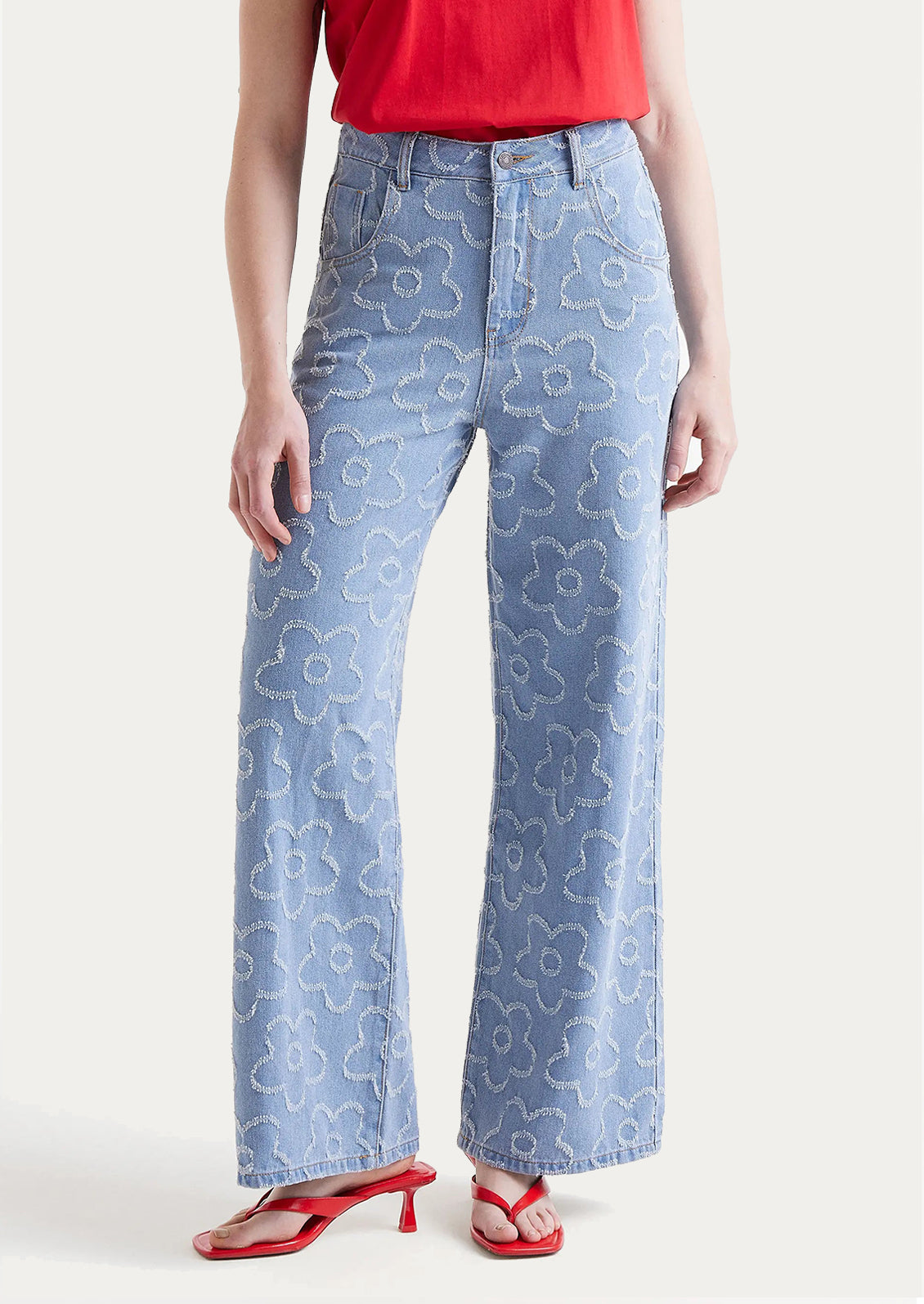 A woman wearing a pair of denim jeans with jacquard flower pattern throughout.
