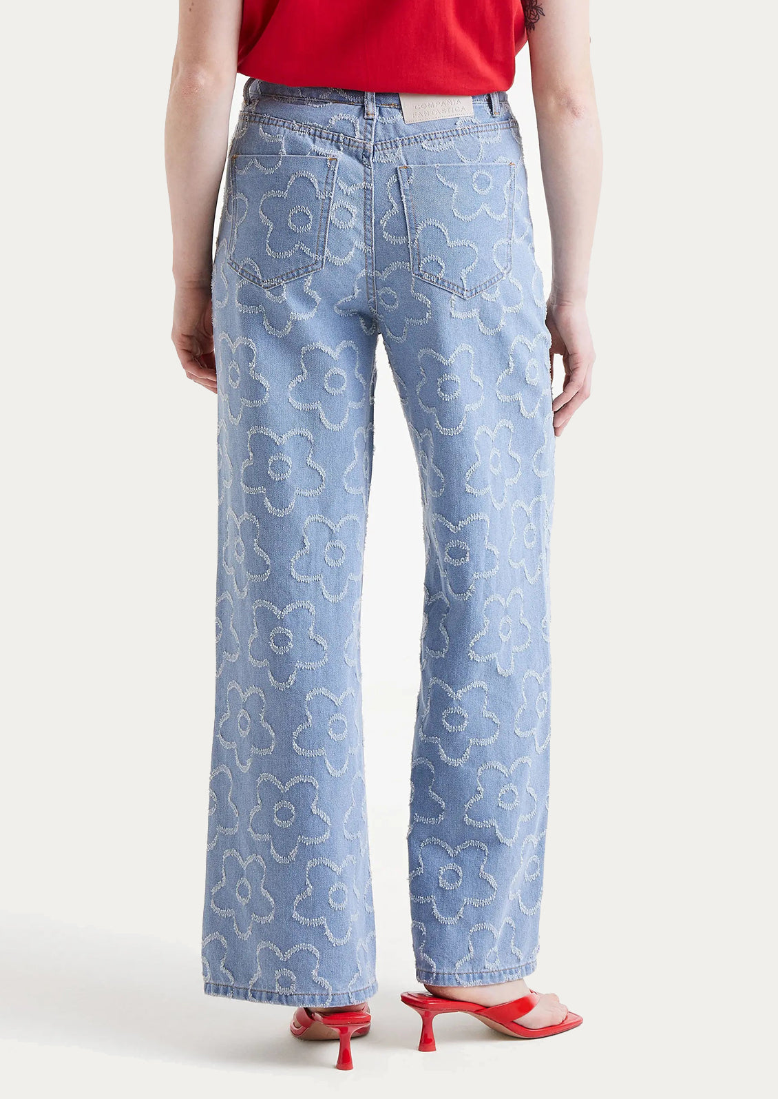 A woman wearing a pair of denim jeans with jacquard flower pattern throughout.
