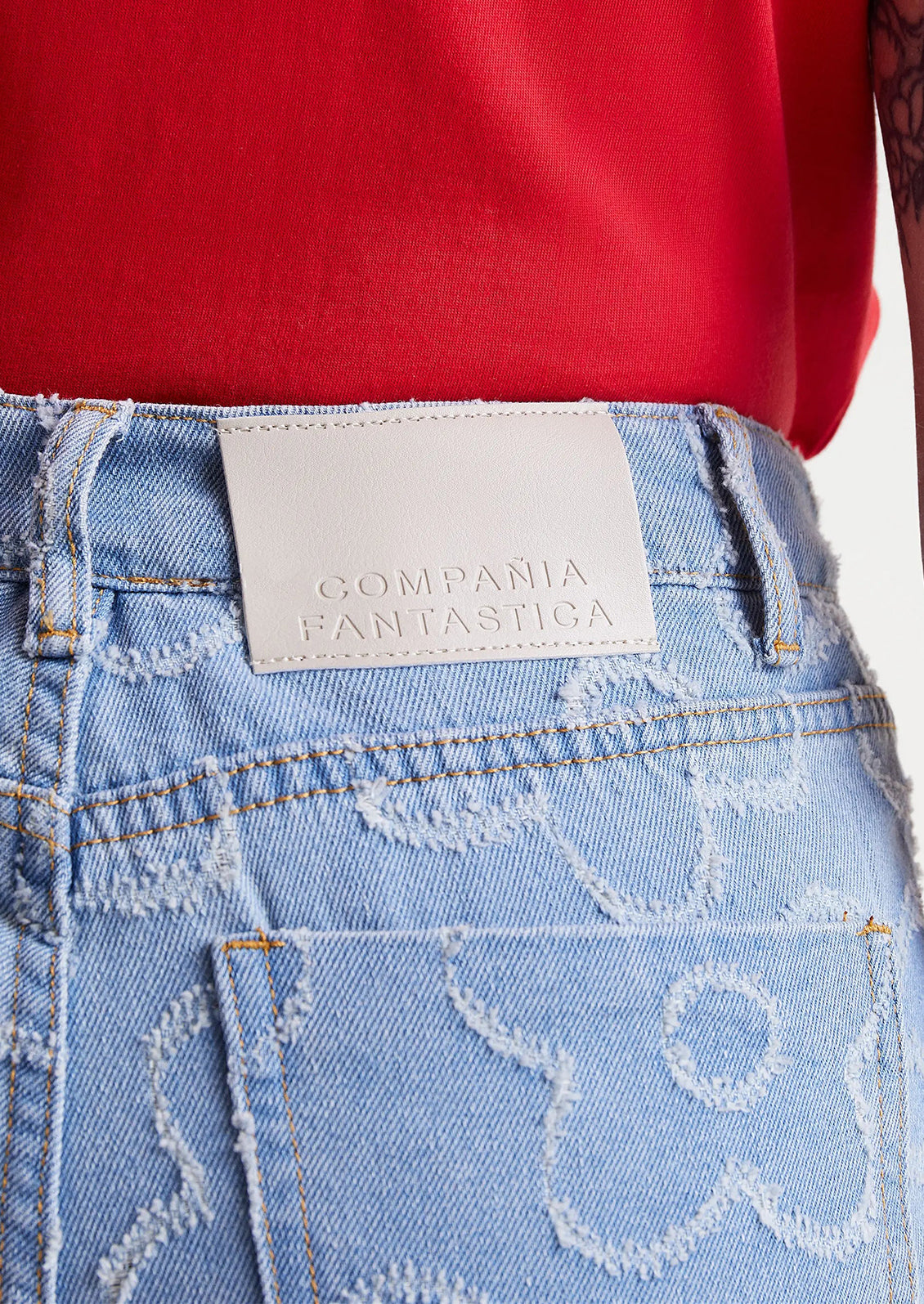 A woman wearing a pair of denim jeans with jacquard flower pattern throughout.