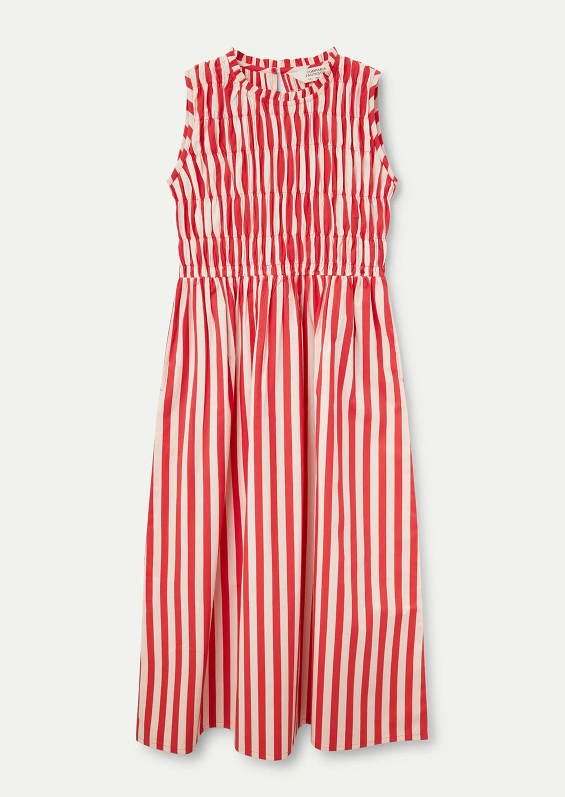 A woman wearing a cotton dress with smocked bodice in vertical red stripes.