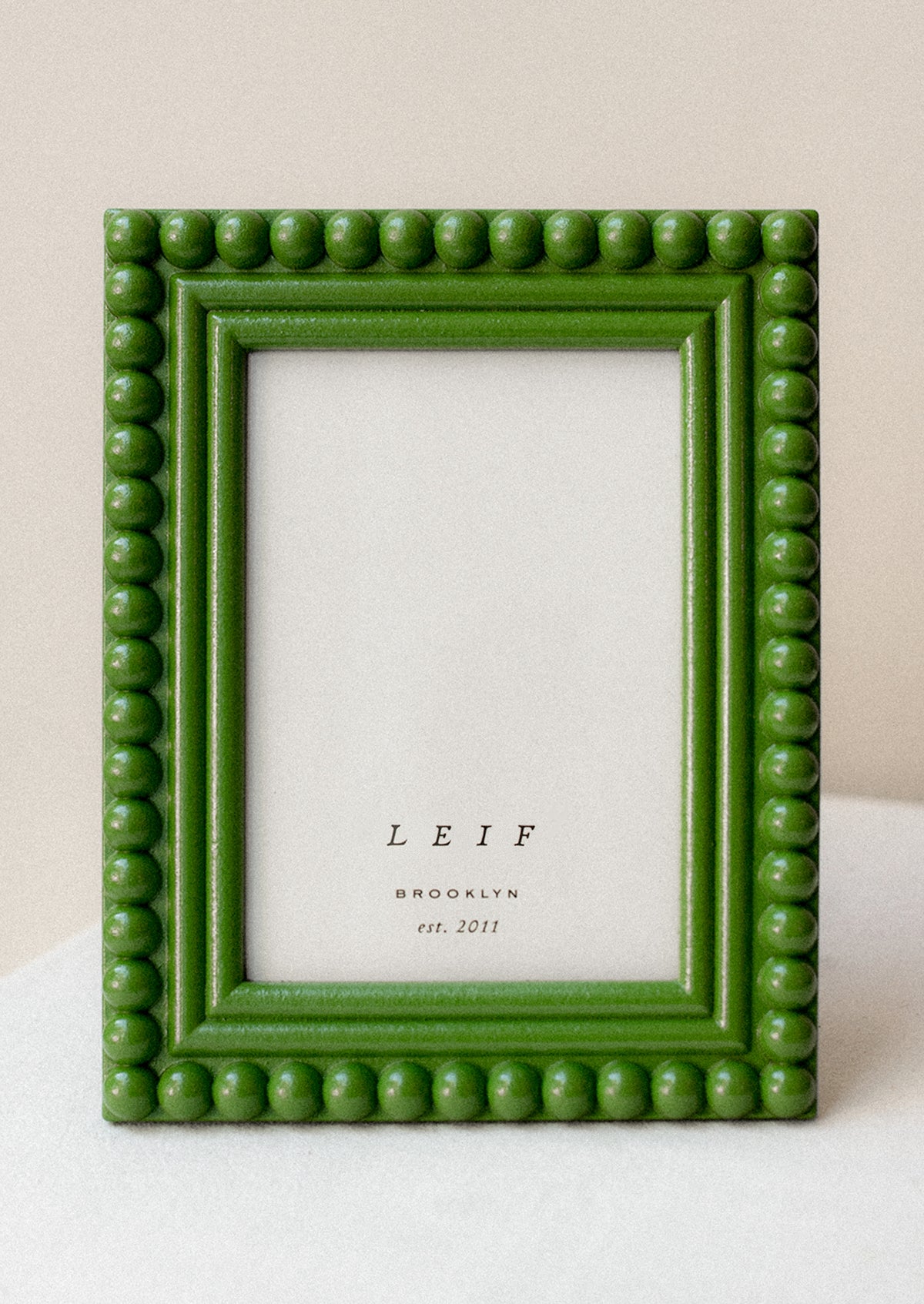 A picture frame with hobnail border in grass green lacquer.