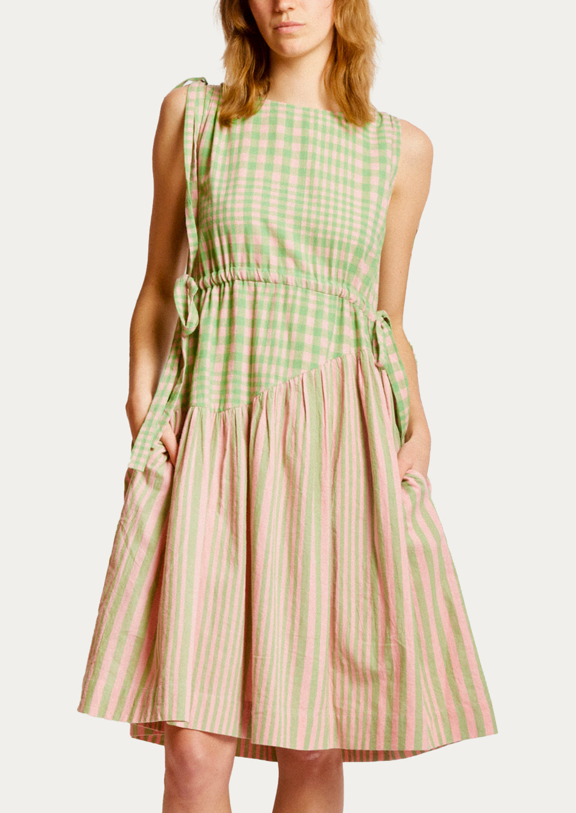 A person wearing a short dress in green and pink striped mix stripe and gingham.