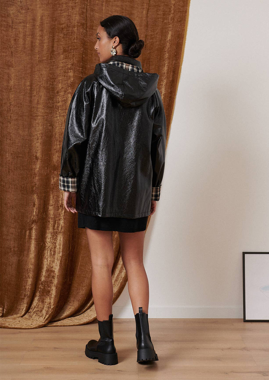 A woman wearing a patent jacket in black with plaid lining.