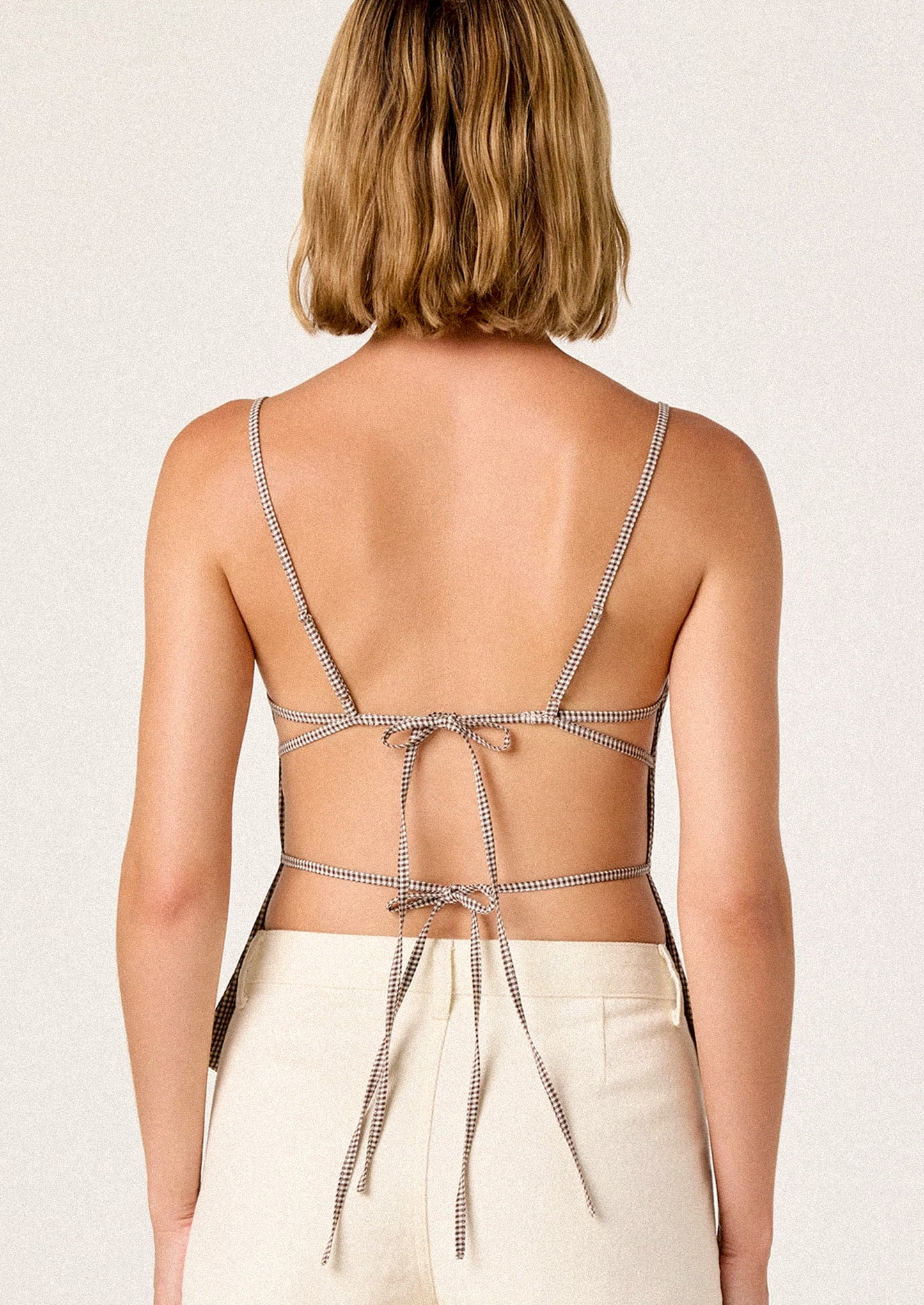 Woman wearing a strappy top with a plain background